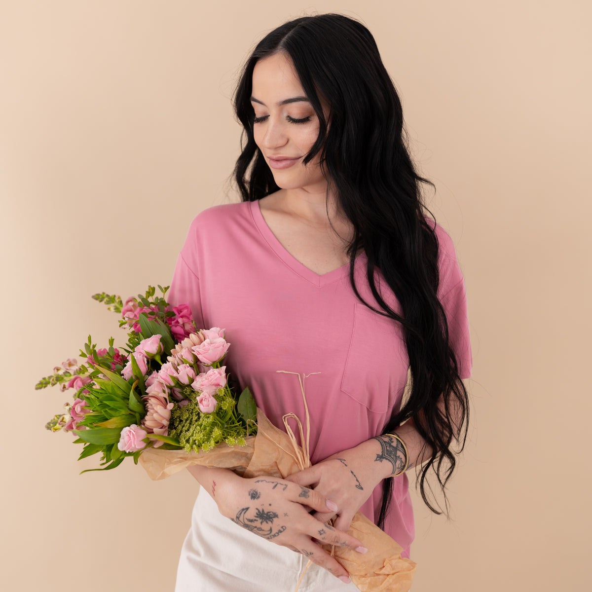 Woman modeling Kyte Baby Women’s Relaxed Fit V-Neck in Apple Blossom holding bouquet of flowers