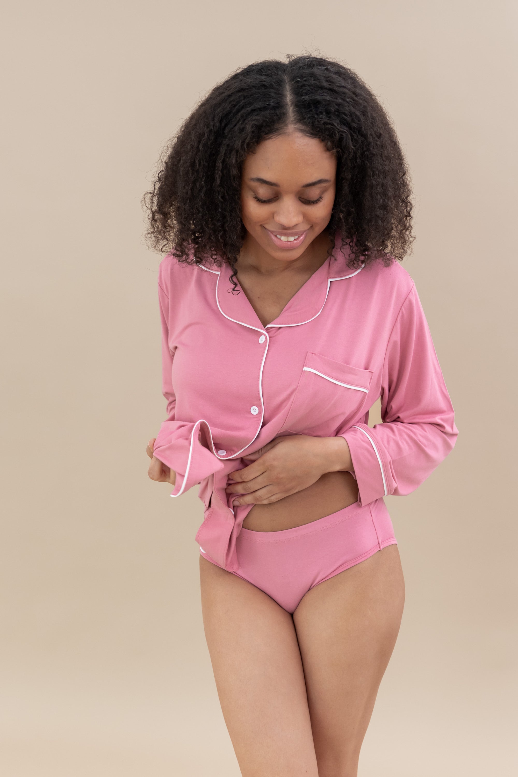 Smiling model wearing pink underwear with matching button up long sleeve pajama top