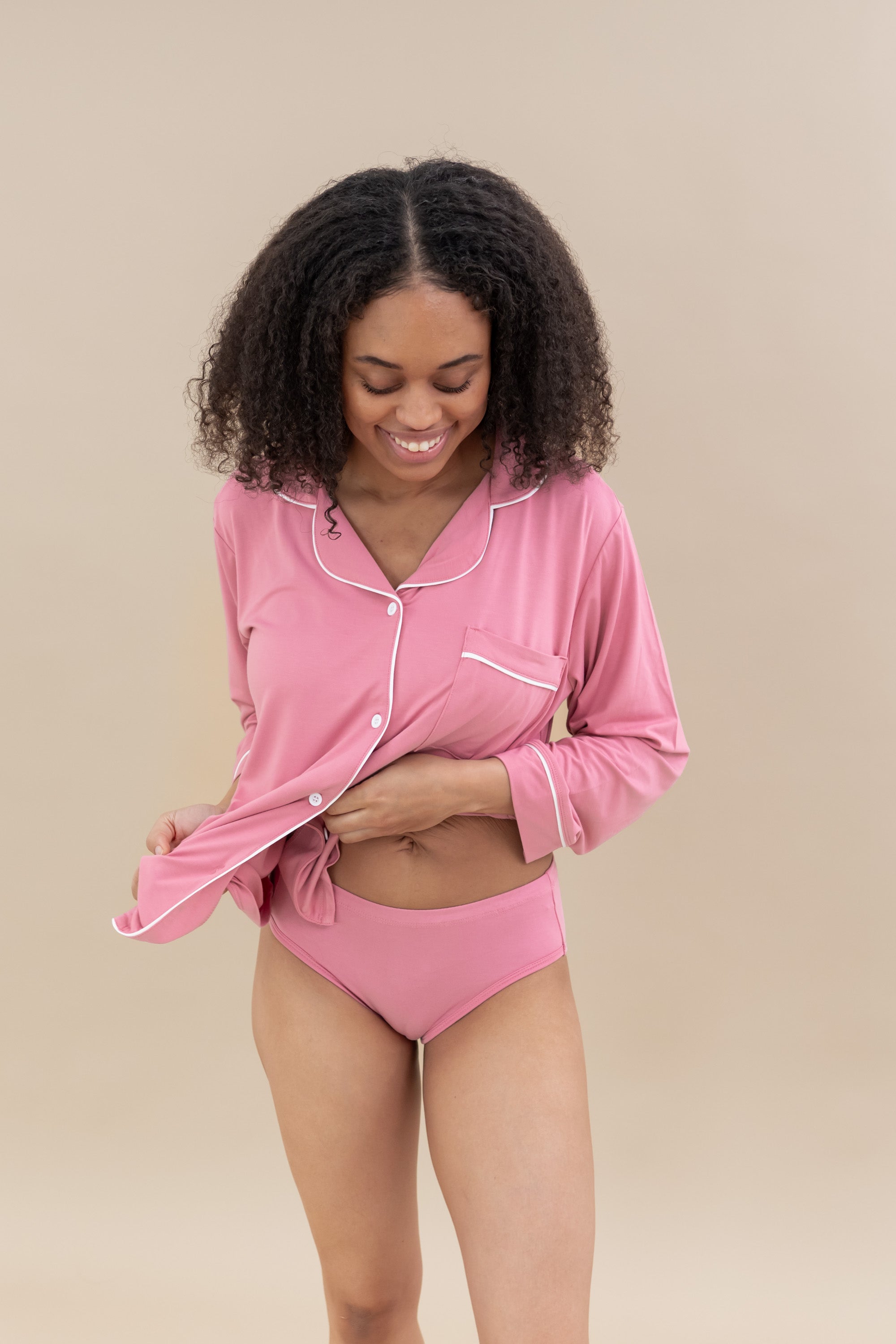 Smiling model wearing pink underwear with matching button up long sleeve pajama top