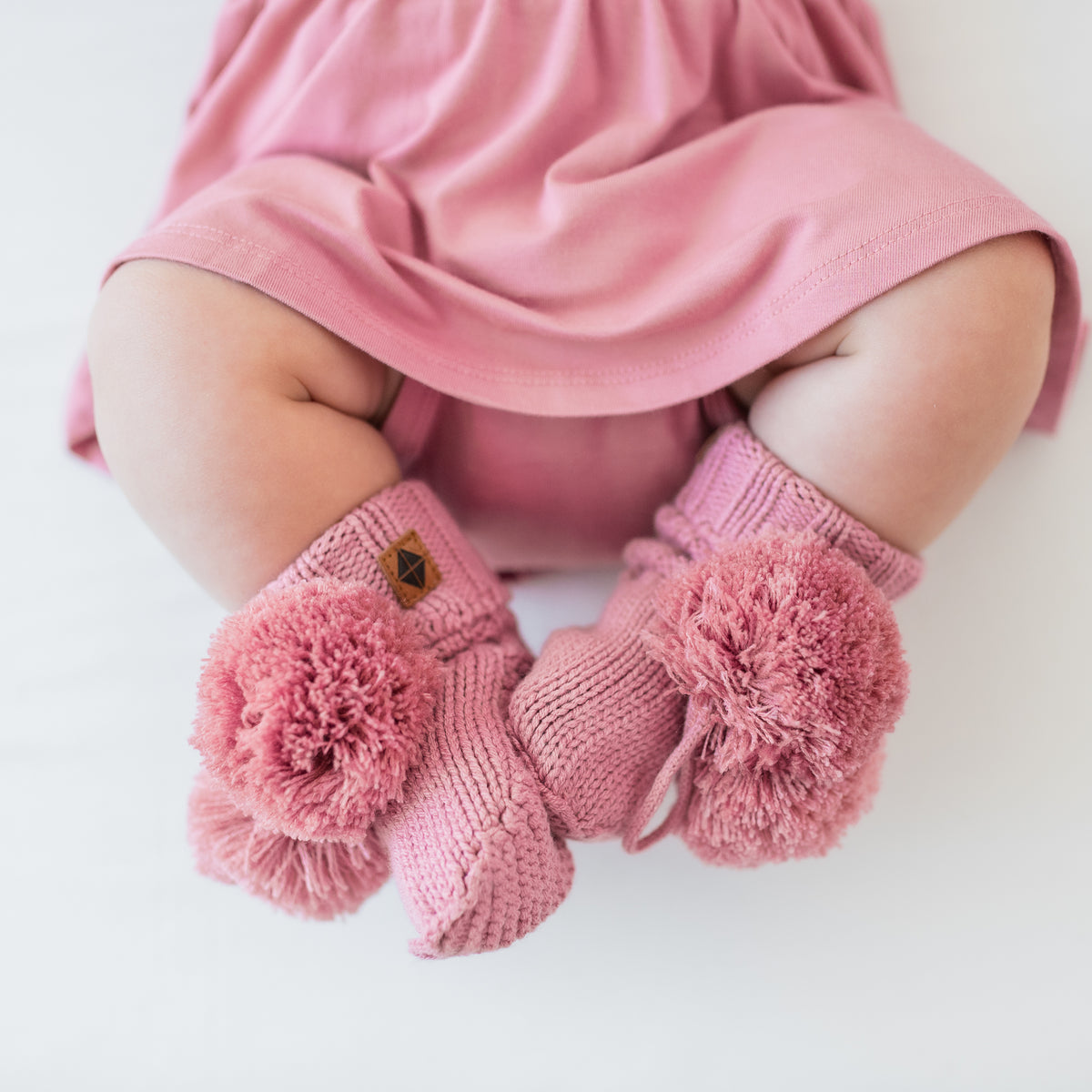 Knit Booties in Apple Blossom shown on an infant