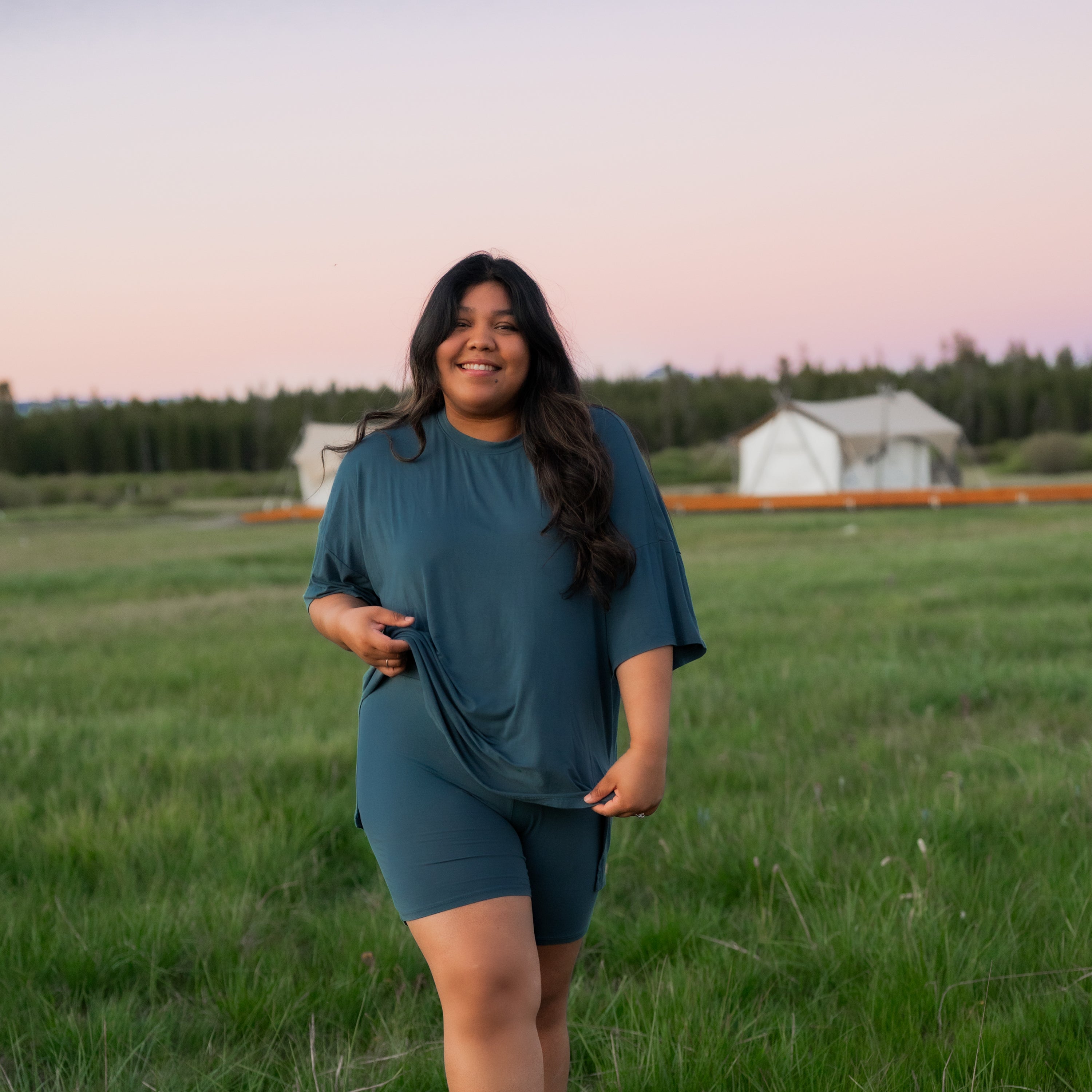 Smiling female model standing in a field wearing the Women’s Biker Short Set in Atlantic