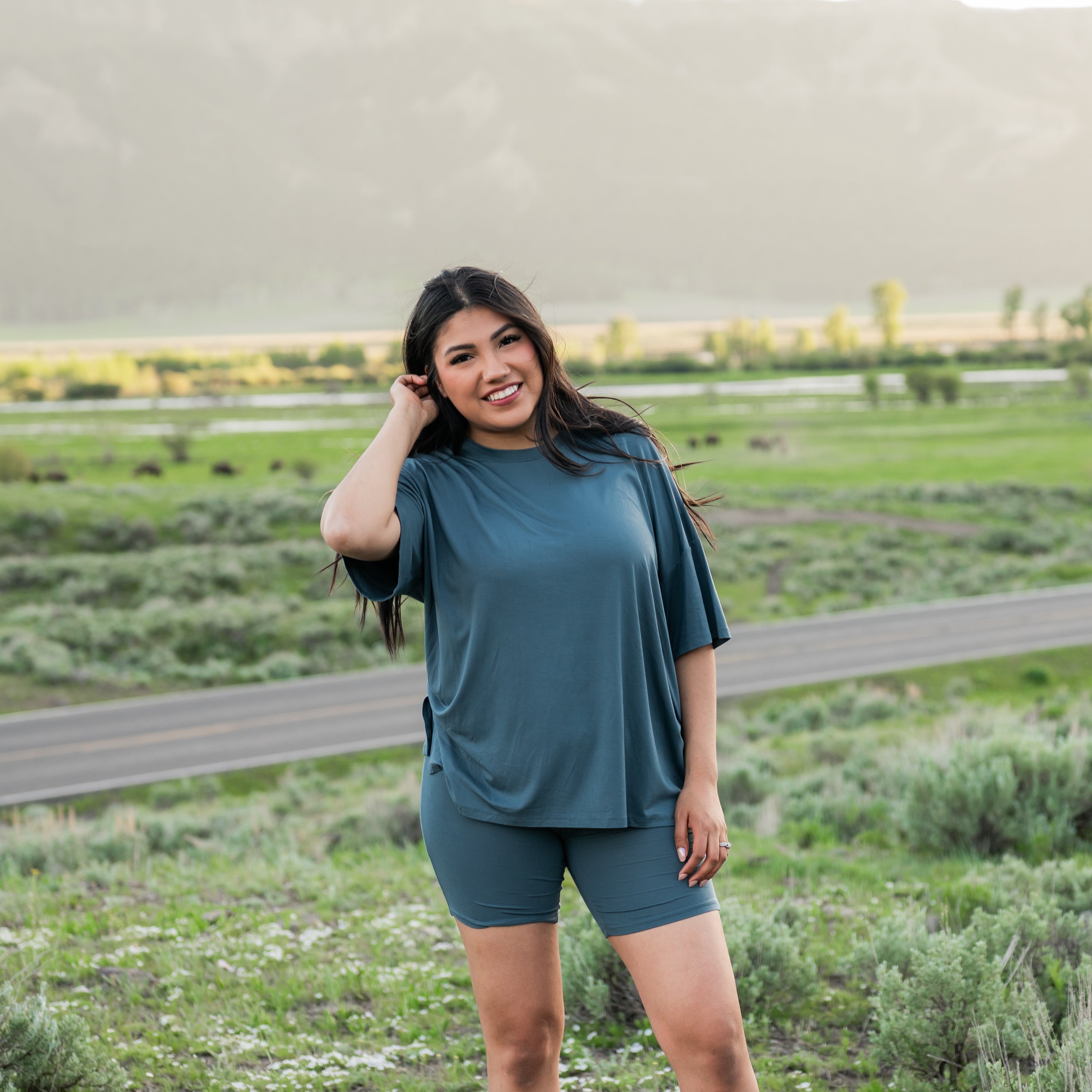 Smiling female model standing in a field wearing the Women’s Biker Short Set in Atlantic