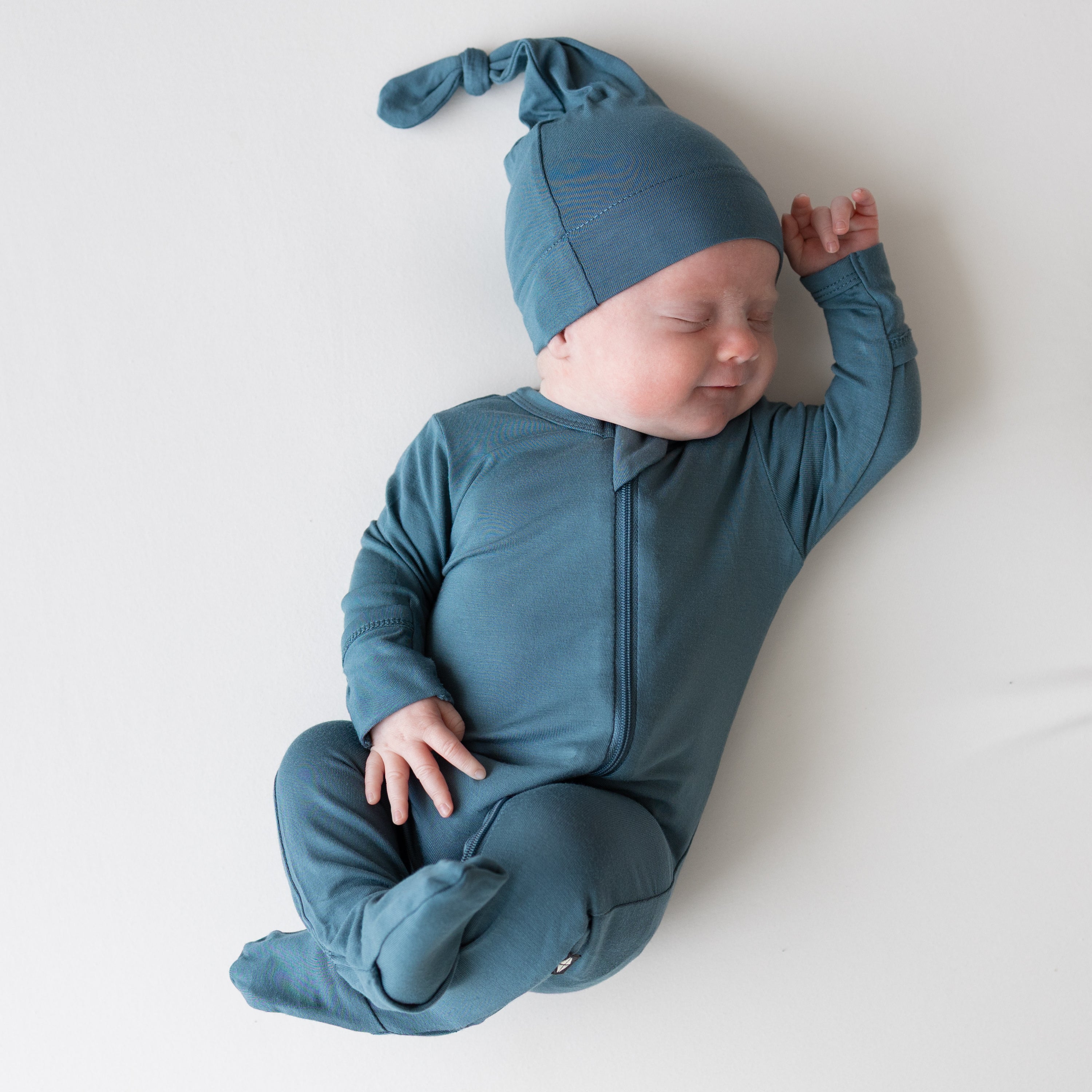 Baby wearing Zippered Footie in Atlantic and matching cap