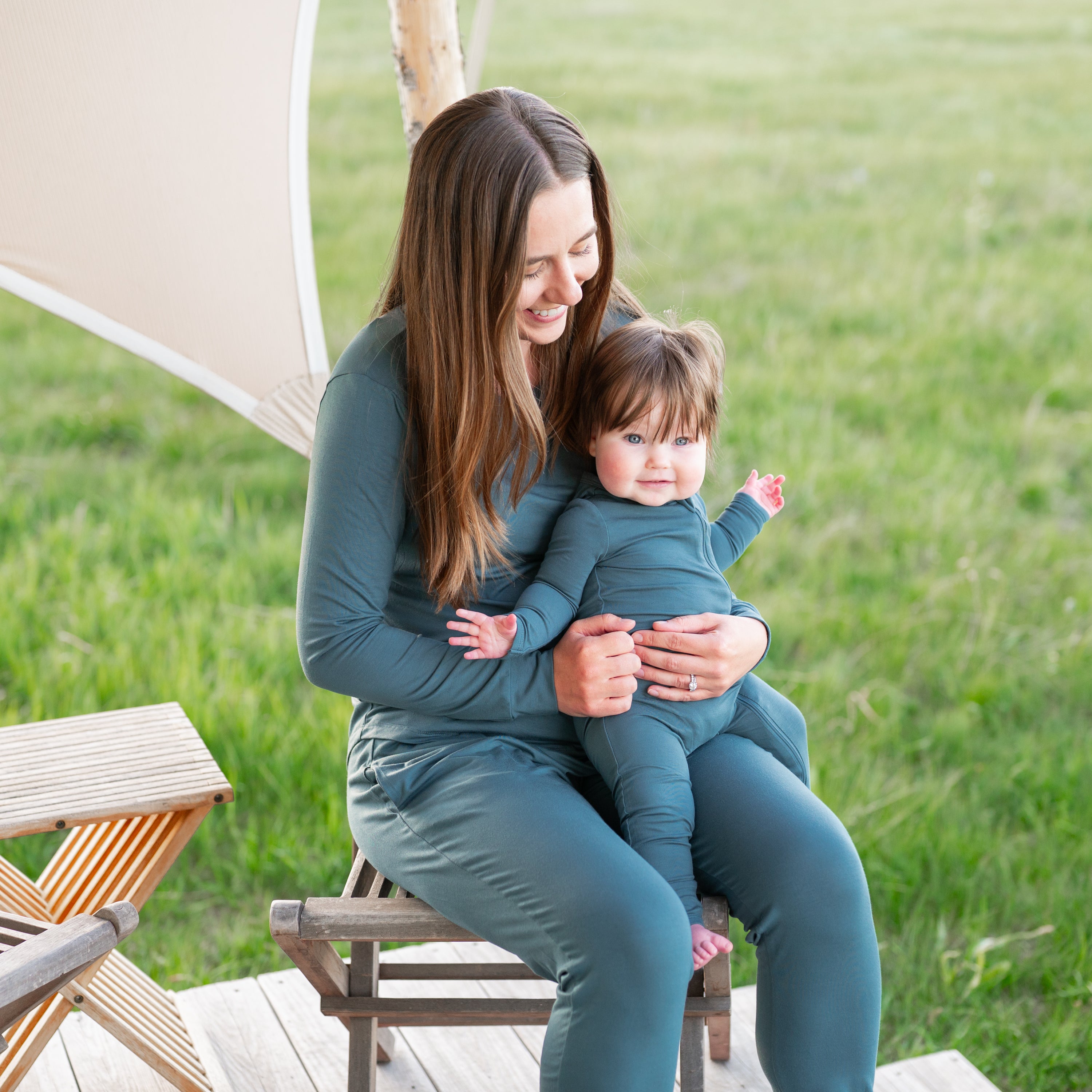 Mother holding infant wearing the Zippered Romper in Atlantic on her lap