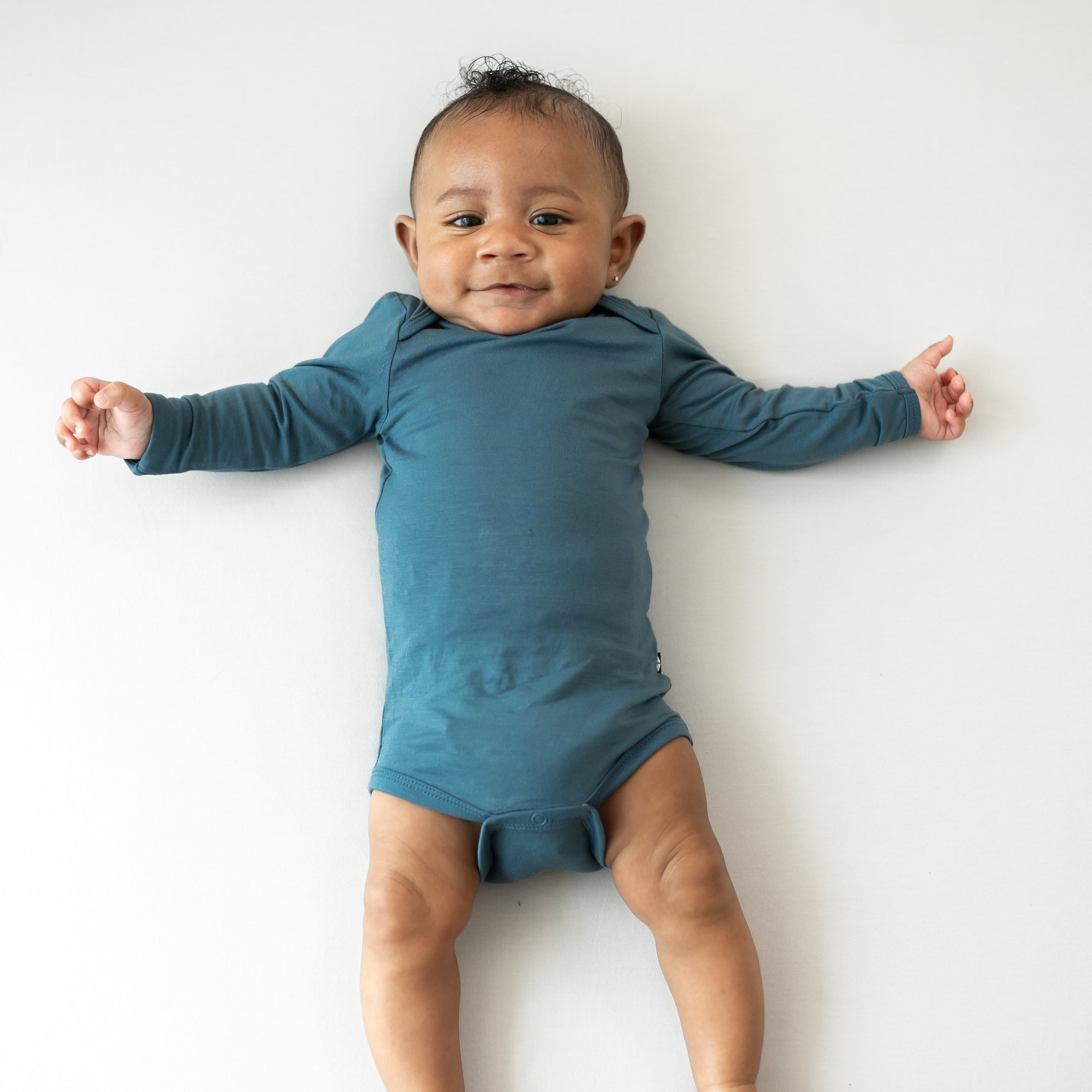 Infant laying down wearing the Long Sleeve Bodysuit in Atlantic