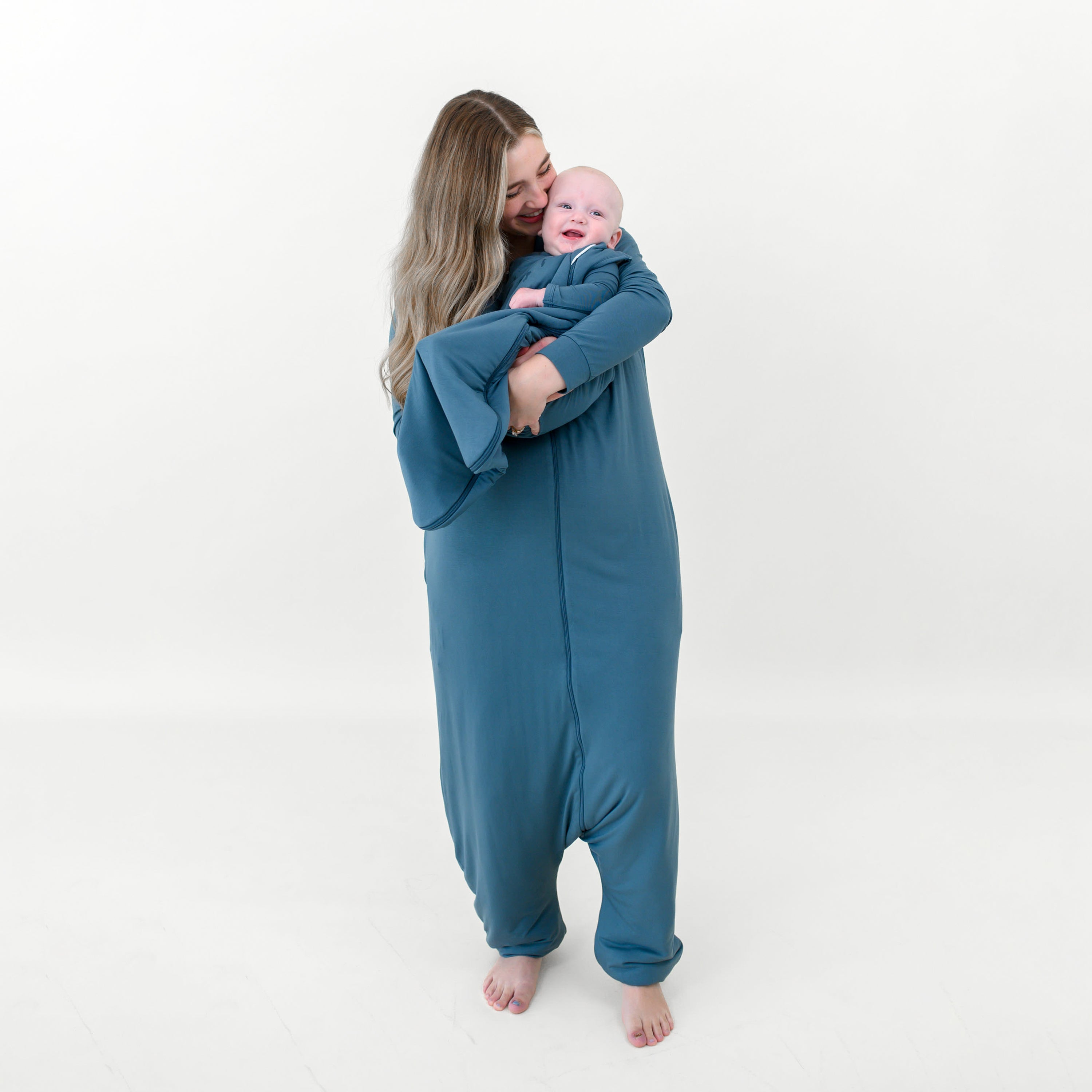 Adult wearing the Adult Sleep Bag Walker in Atlantic holding infant wearing the Sleep Bag walker in Atlantic