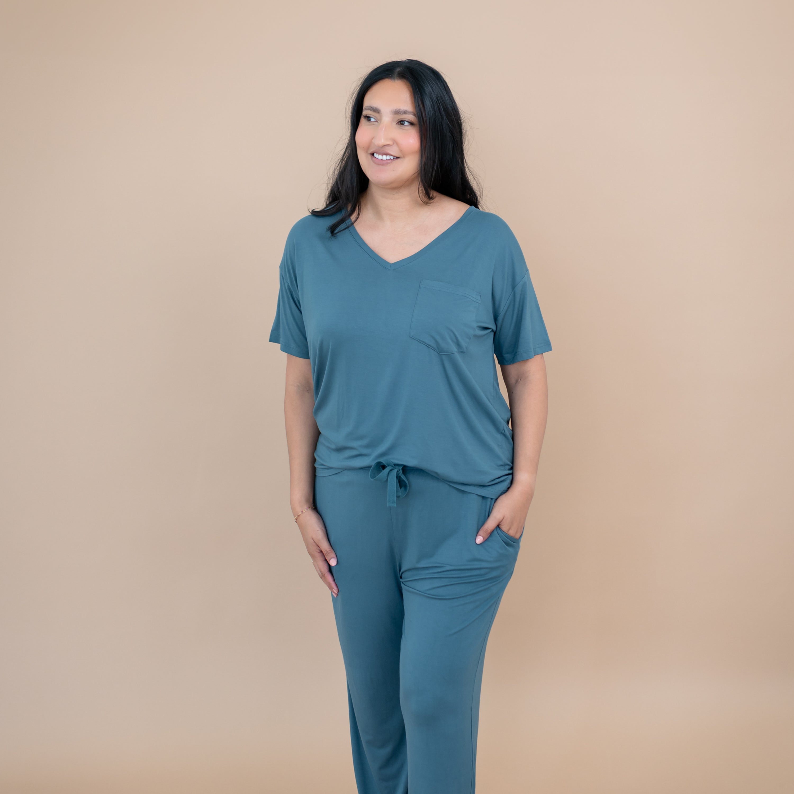 Smiling model standing with hand in pocket of the Women's Lounge Pants in Atlantic paired with a matching women's v-neck