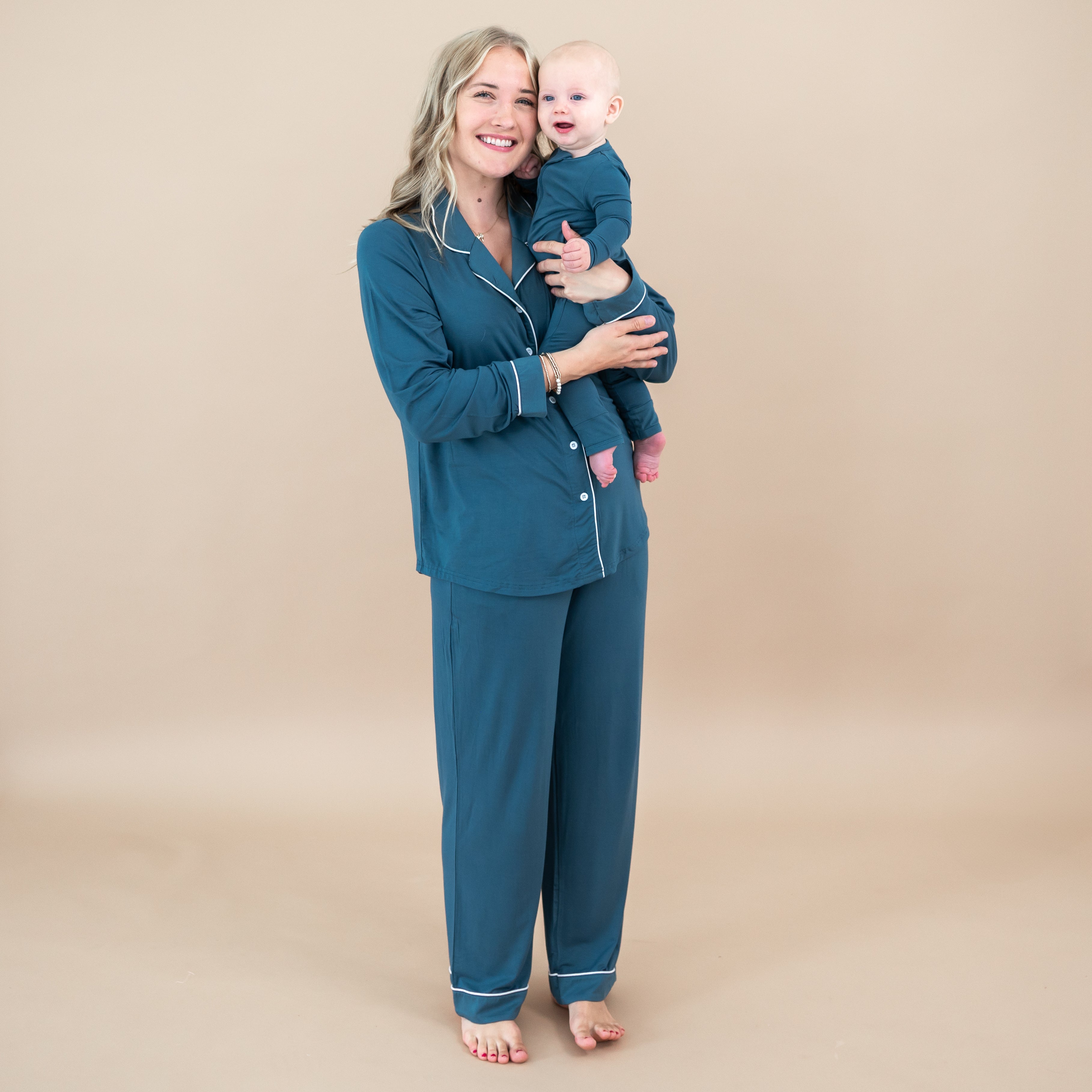 Mom and baby matching in Atlantic. Mother is holding infant wearing the Long-Sleeved Women's Pajama Set in Atlantic with Cloud Trim with the baby wearing the Zippered romper in Atlantic
