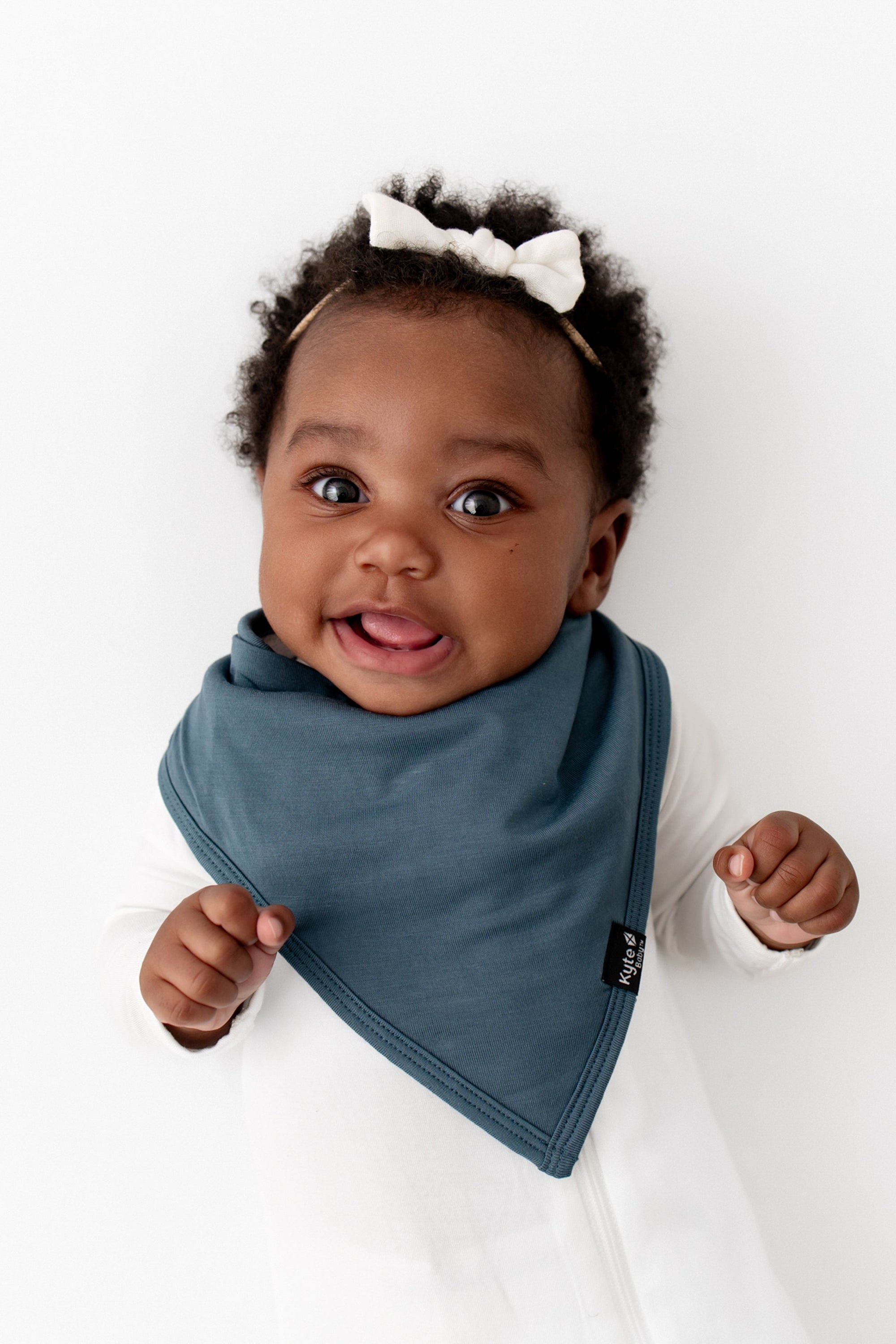 Infant girl wearing the Bib in Atlantic paired with a Cloud Zipper romper and Tiny Nylon Bow