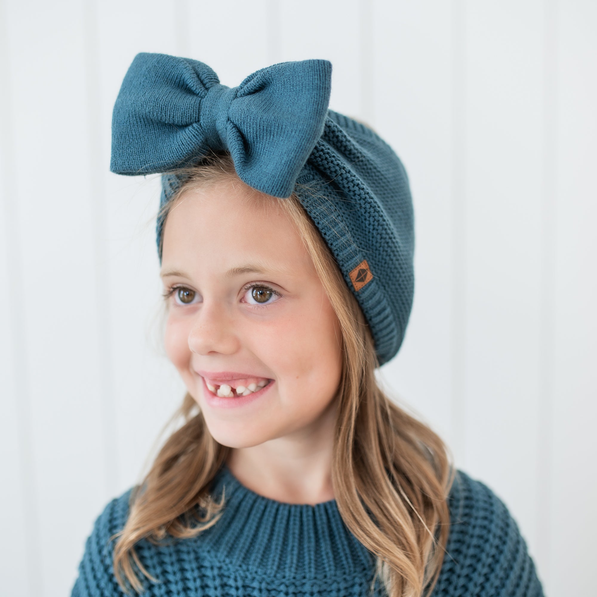 Close up of the Chunky Knit Bow Headband in Atlantic shown on a girl model