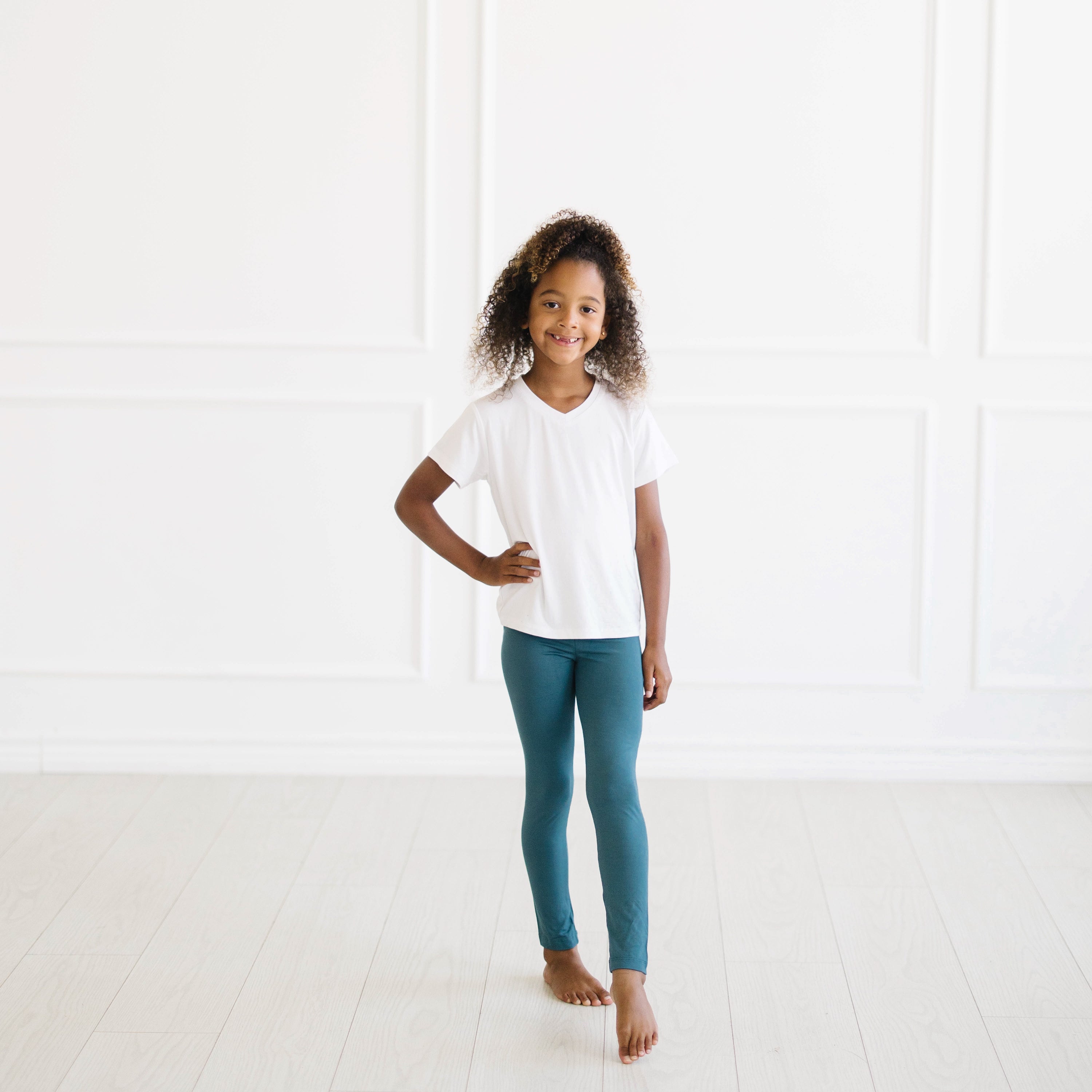 Kid standing with one hand on hip wearing the Toddler Leggings in Atlantic and Snow V-neck