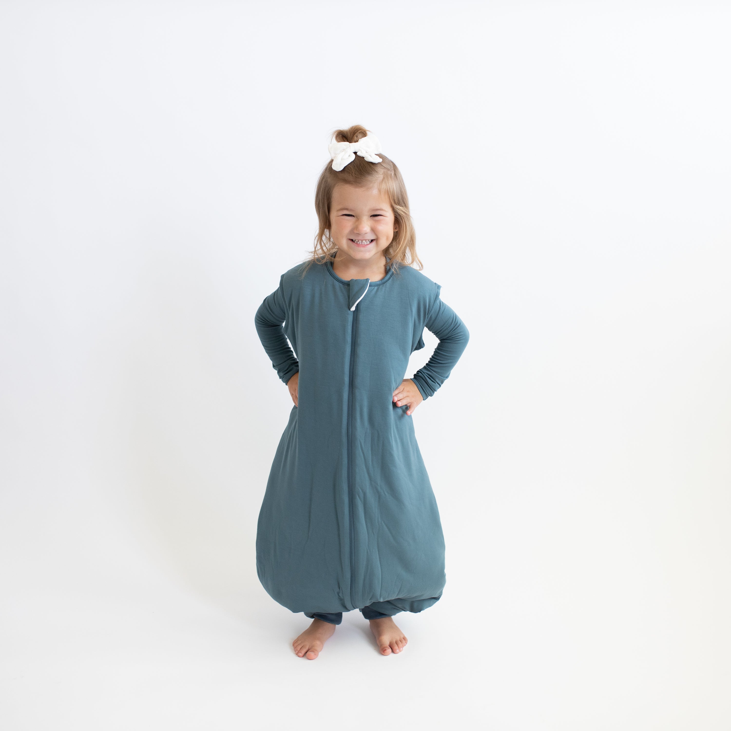 Smiling girl standing with hands on her hips wearing the Sleep Bag Walker in Atlantic 2.5