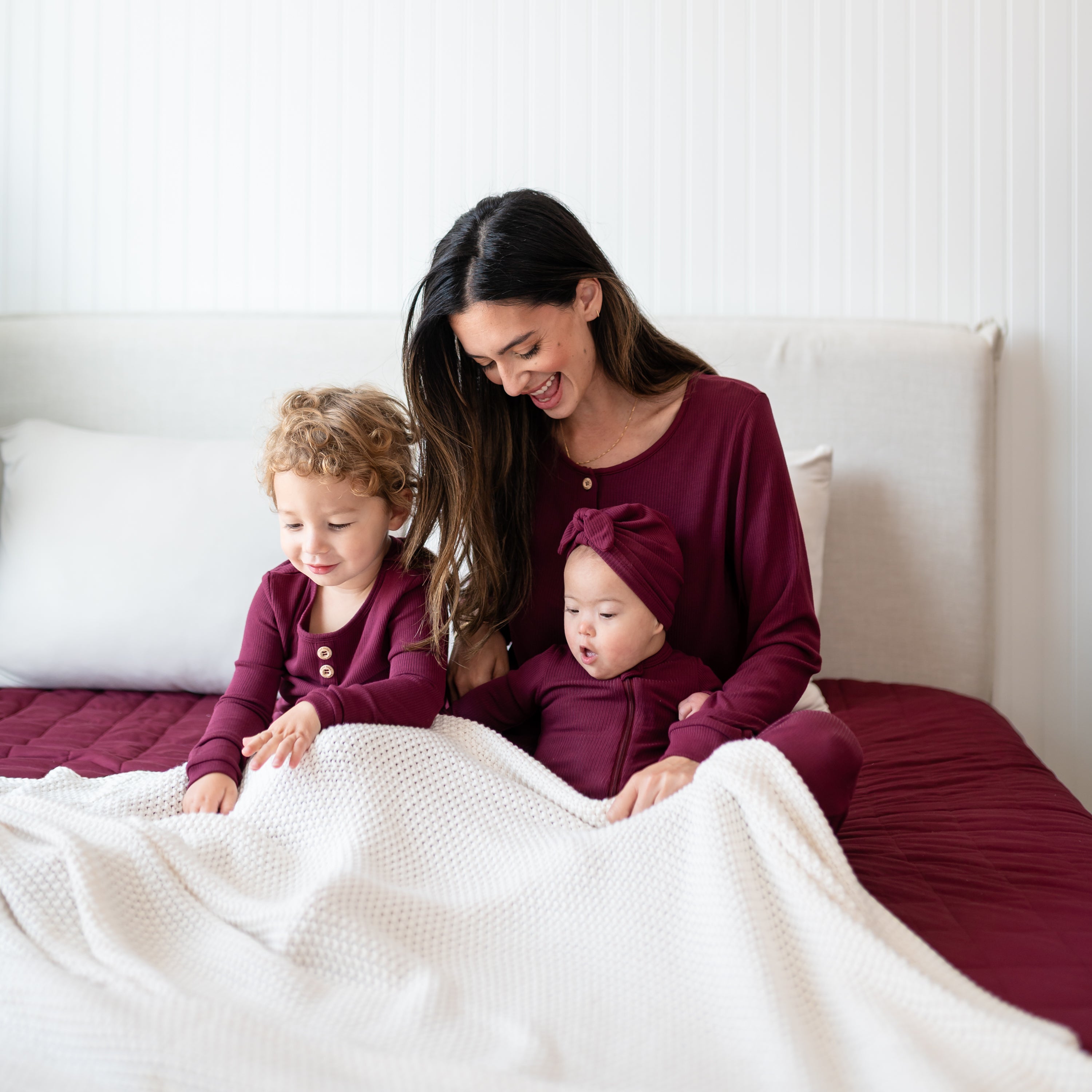 Family of three sitting in bed matching in Burgundy Ribbed items