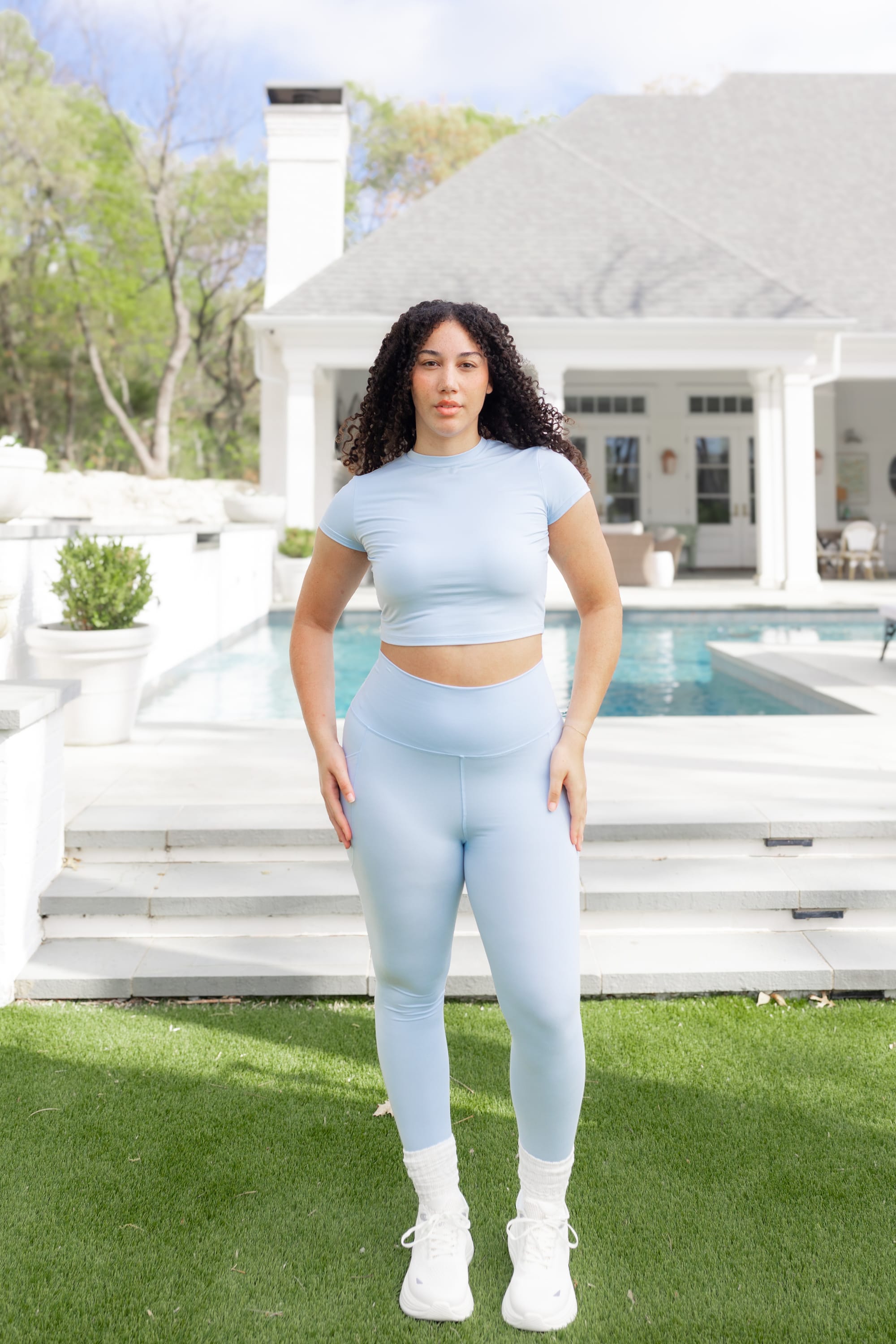 Female posing in front of a pool wearing the Bamboo Flex Baby Tee in Breeze with matching bamboo flex leggings