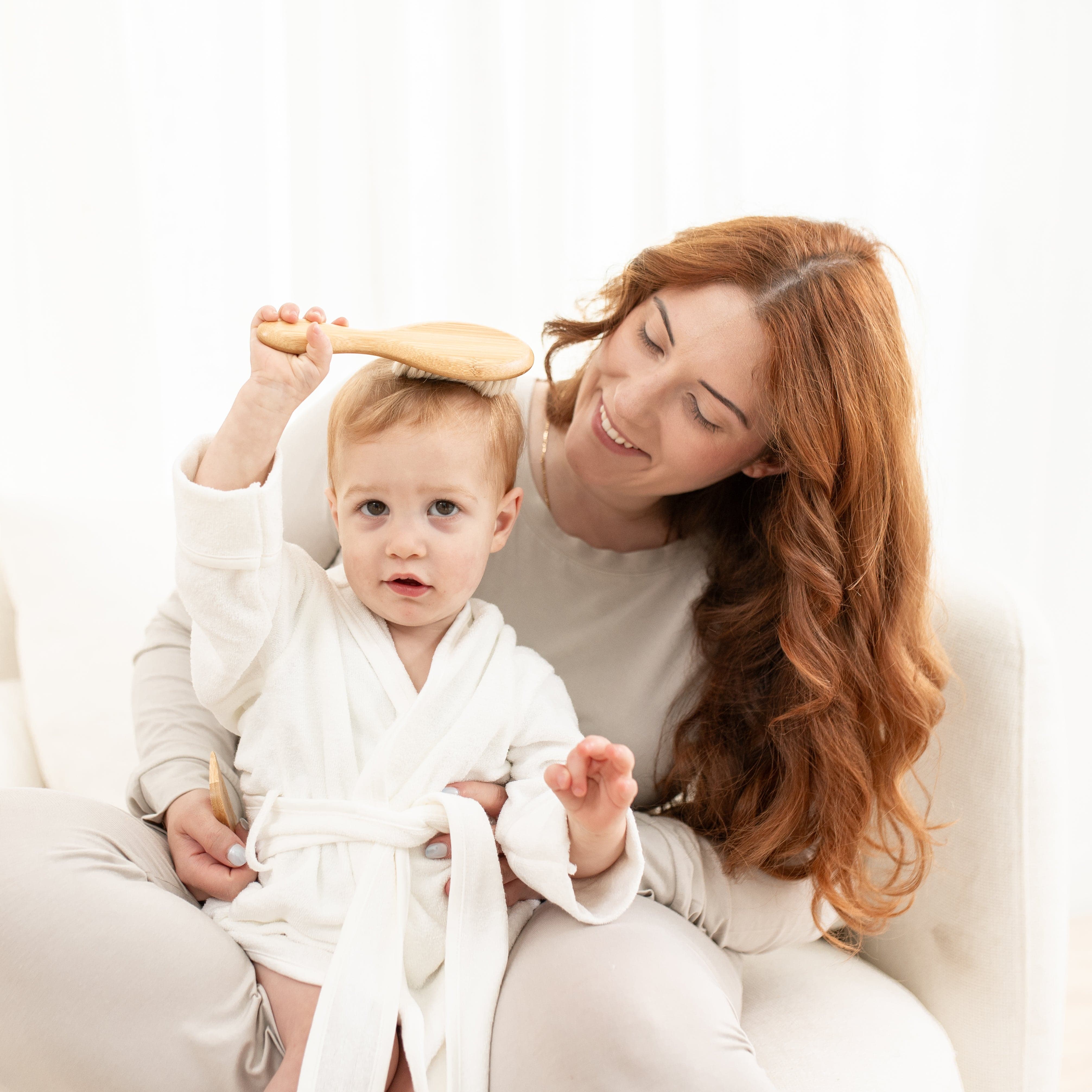Mom and toddler sitting while toddler brushes their own hair with Crale Cap Brush