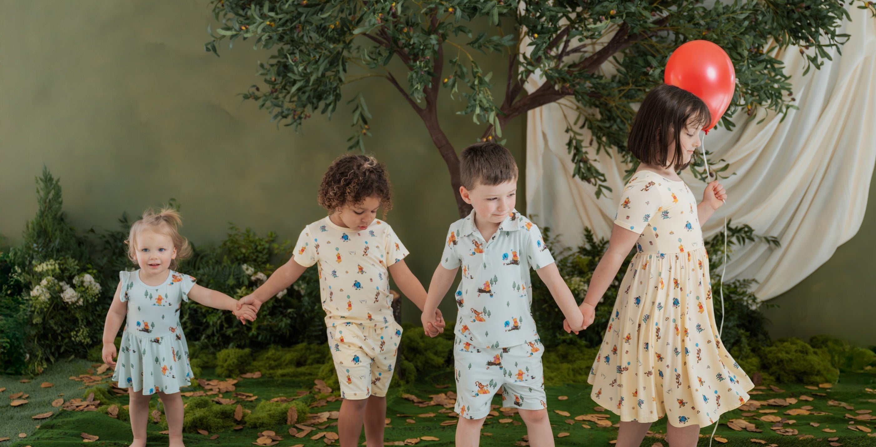 4 children wearing Disney Winnie the Pooh apparel in a wood setting