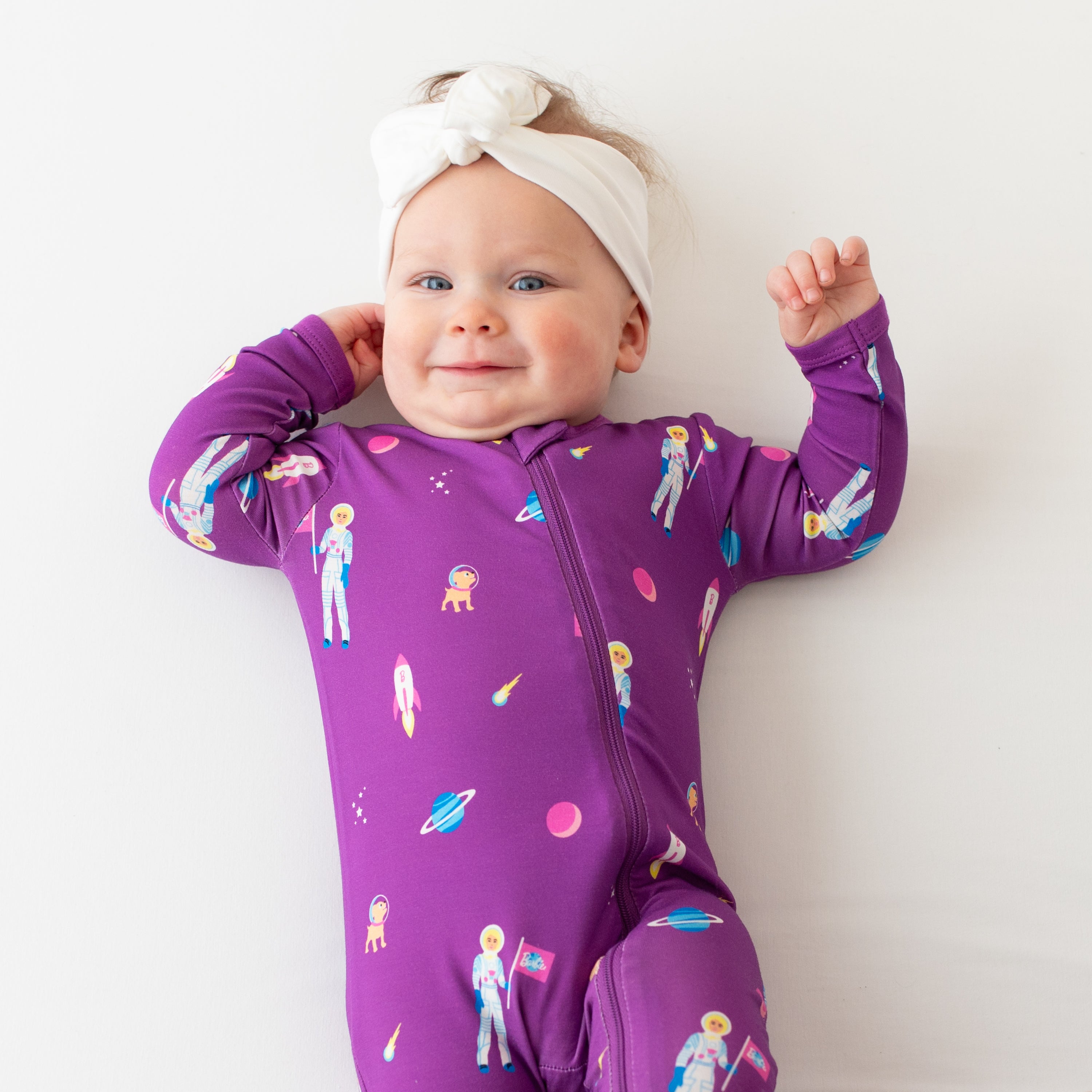 Close up of infant wearing Kyte Baby Zippered Footie Pajamas in Barbie™ Astronaut