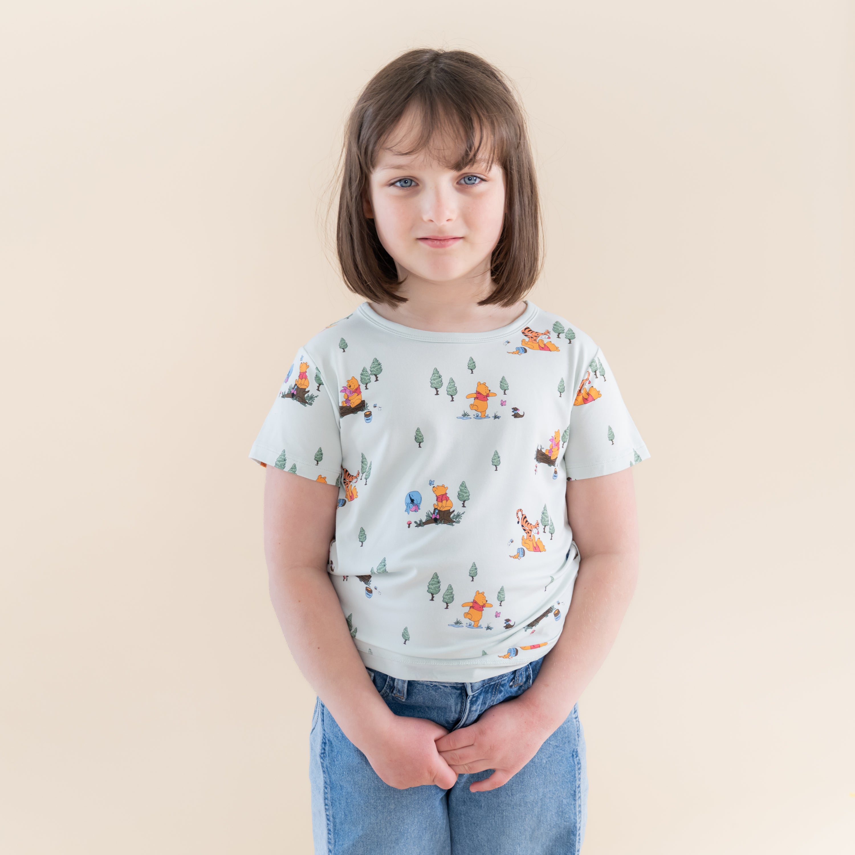 Young girl posing wearing the Toddler Basic Tee in Winnie the Pooh Hundred Acre Wood paired with jeans