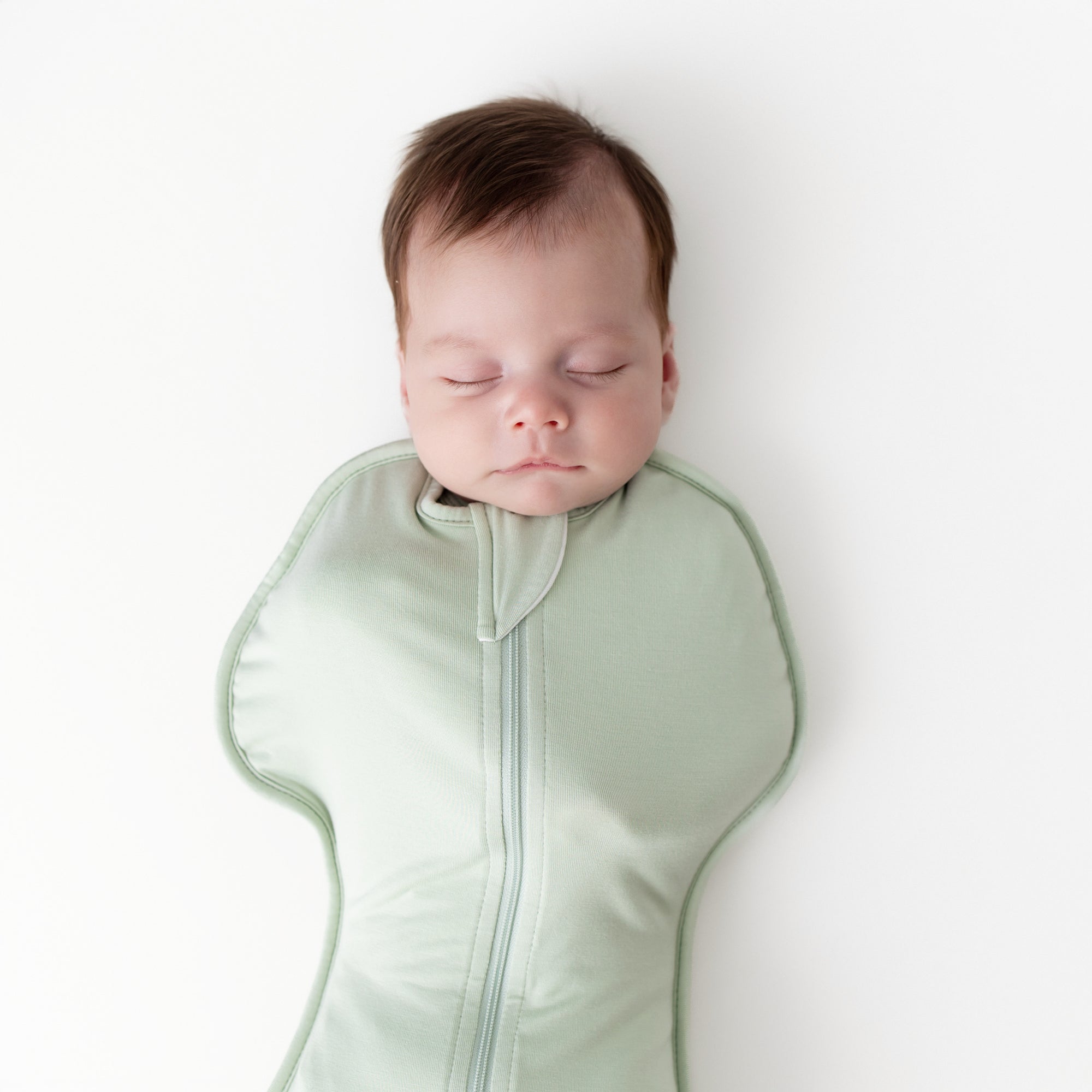 Close up of sleeping baby wearing the Swaddle Bag in Basil 0.5