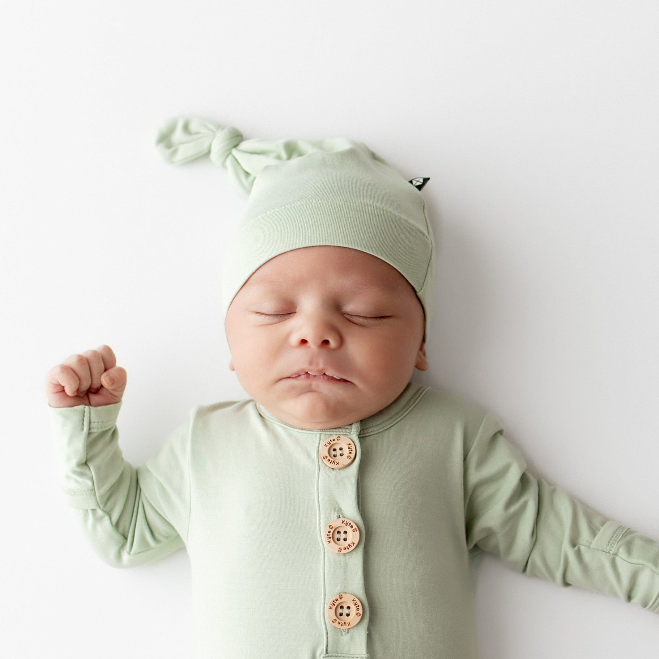 Sleeping newborn wearing the Knotted Cap in Basil