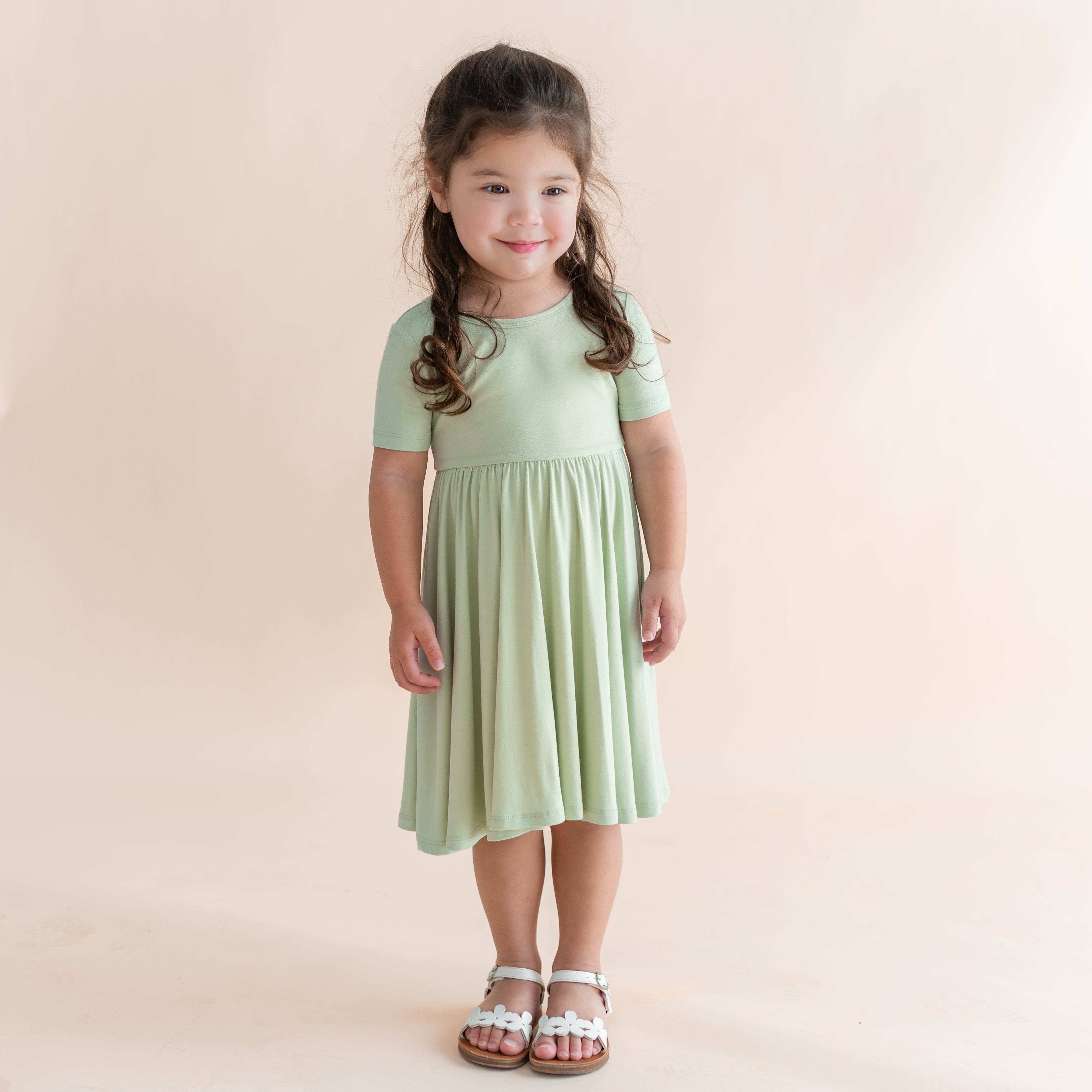 Young girl wearing a light green dress against a beige background