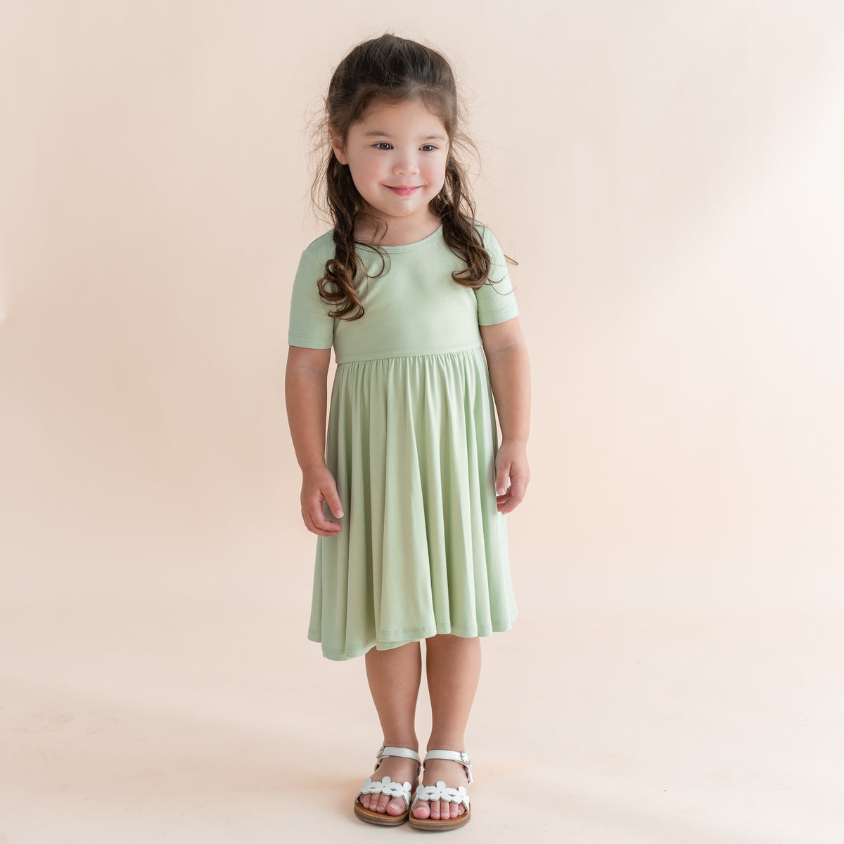 Young girl wearing a light green dress against a beige background
