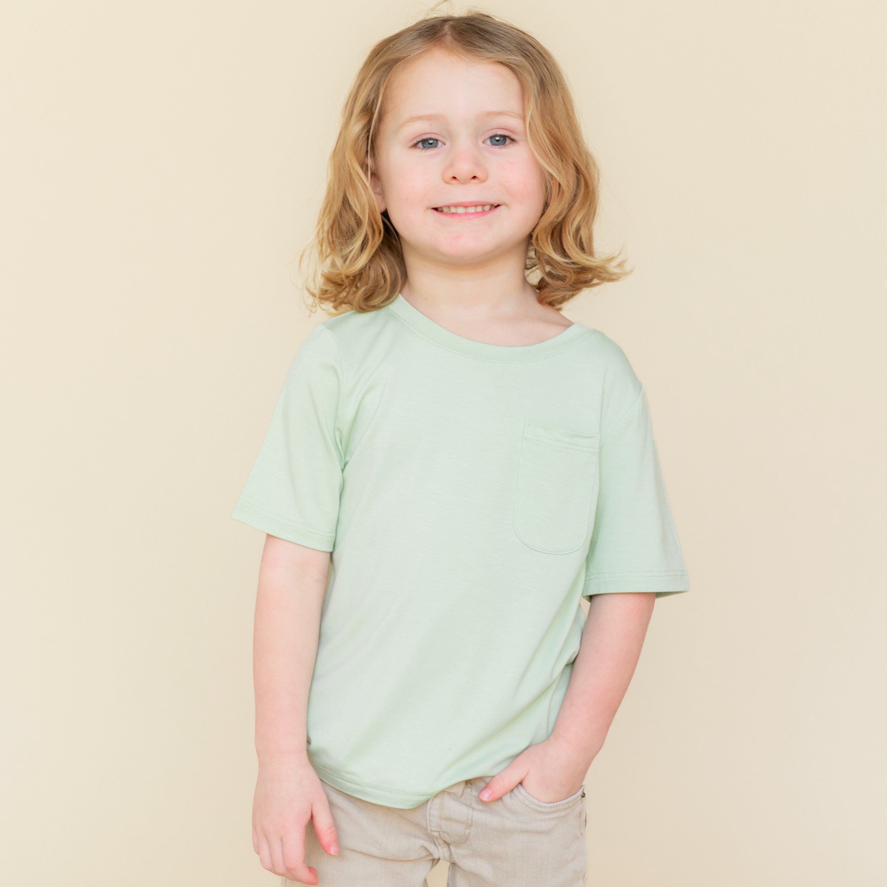 Young child wearing the Toddler Crew Neck Tee in Basil paired with a khaki colored short