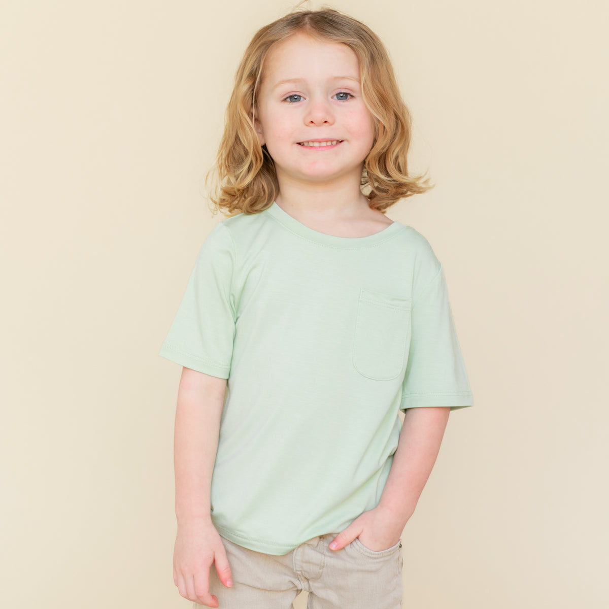 Young child wearing the Toddler Crew Neck Tee in Basil paired with a khaki colored short