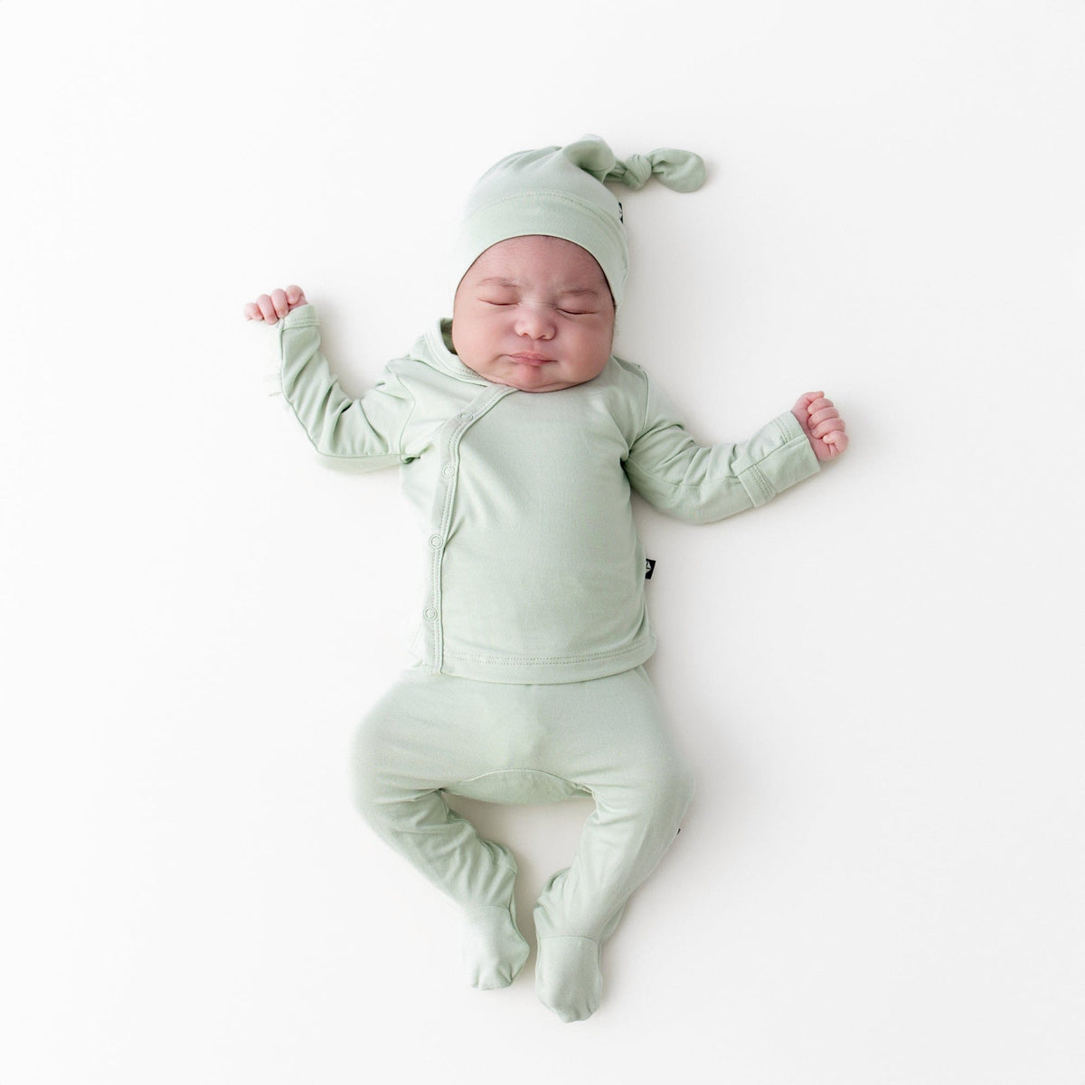 Newborn sleeping wearing the Take Me Home Set with Cap in Basil