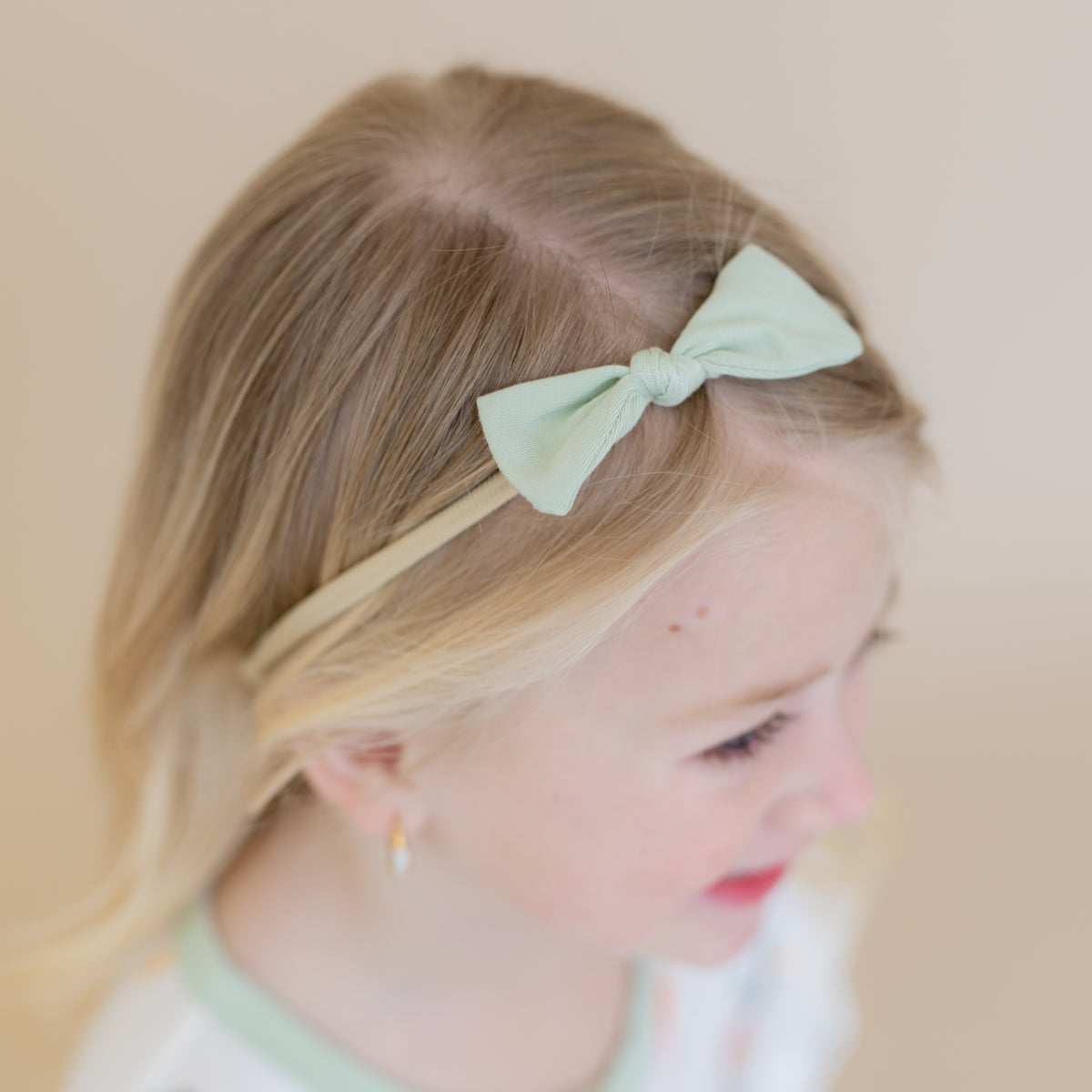 Close up of the Tiny Nylon Bow in Basil shown in a girls hair