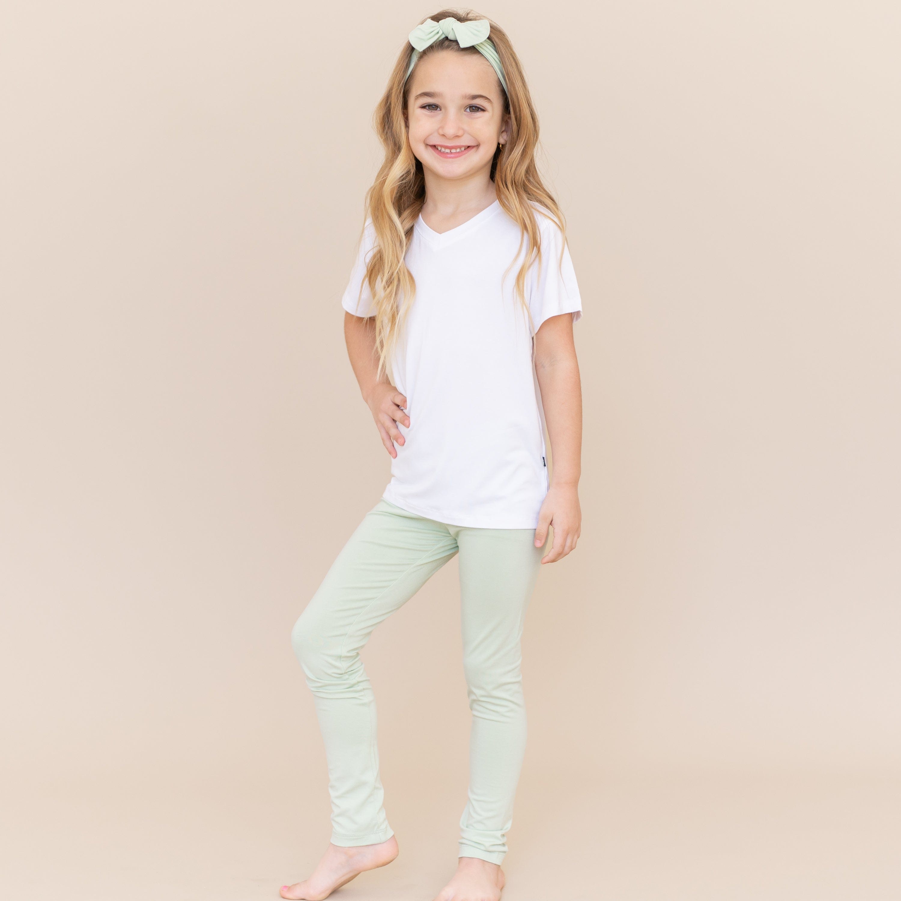 Young girl modeling the Toddler Leggings in Basil and a white v-neck shirt