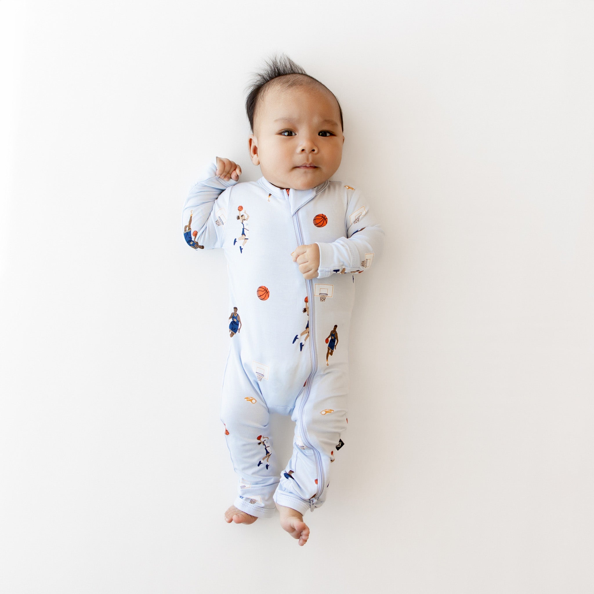 Infant laying down wearing the Zippered Romper in Basketball
