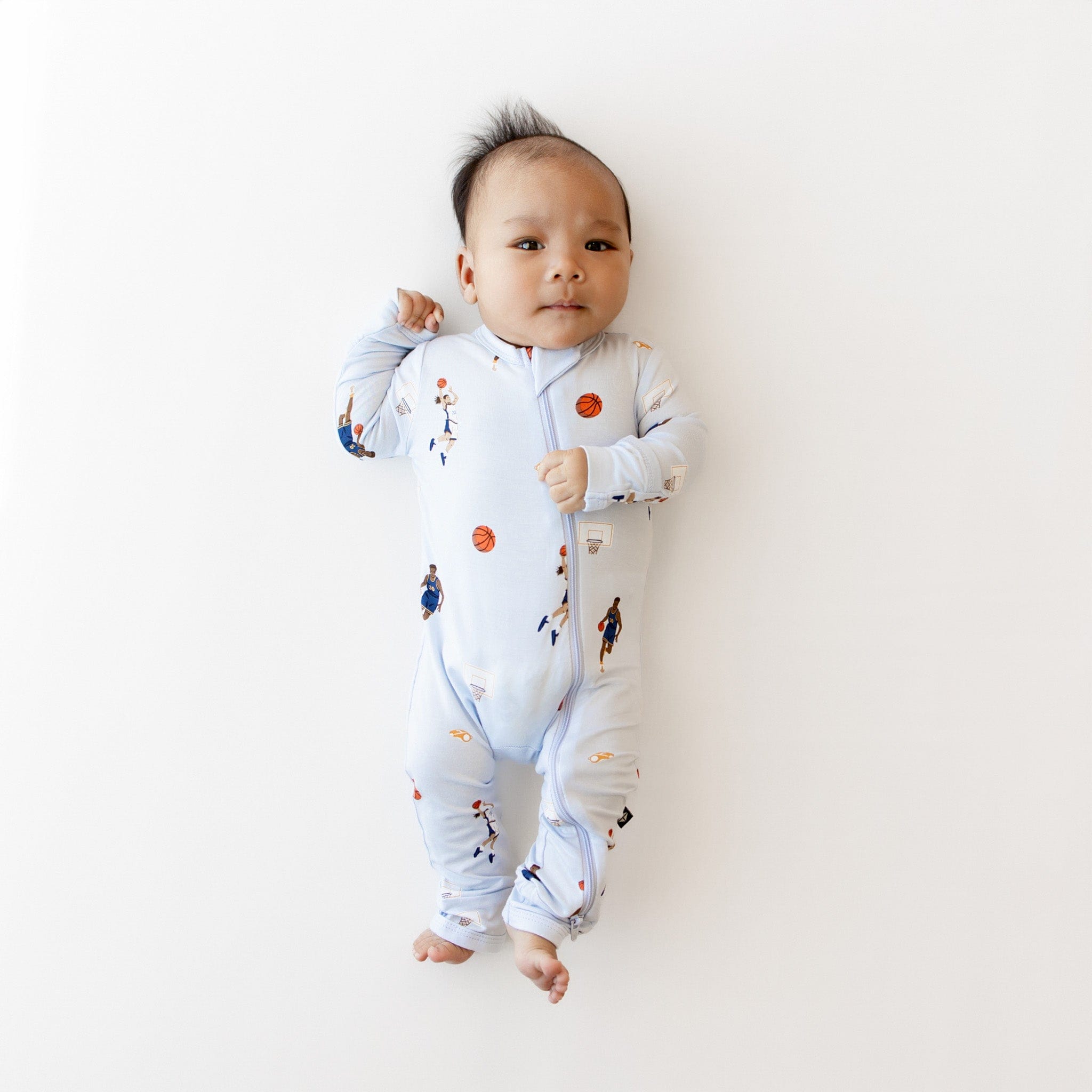 Infant laying down wearing the Zippered Romper in Basketball