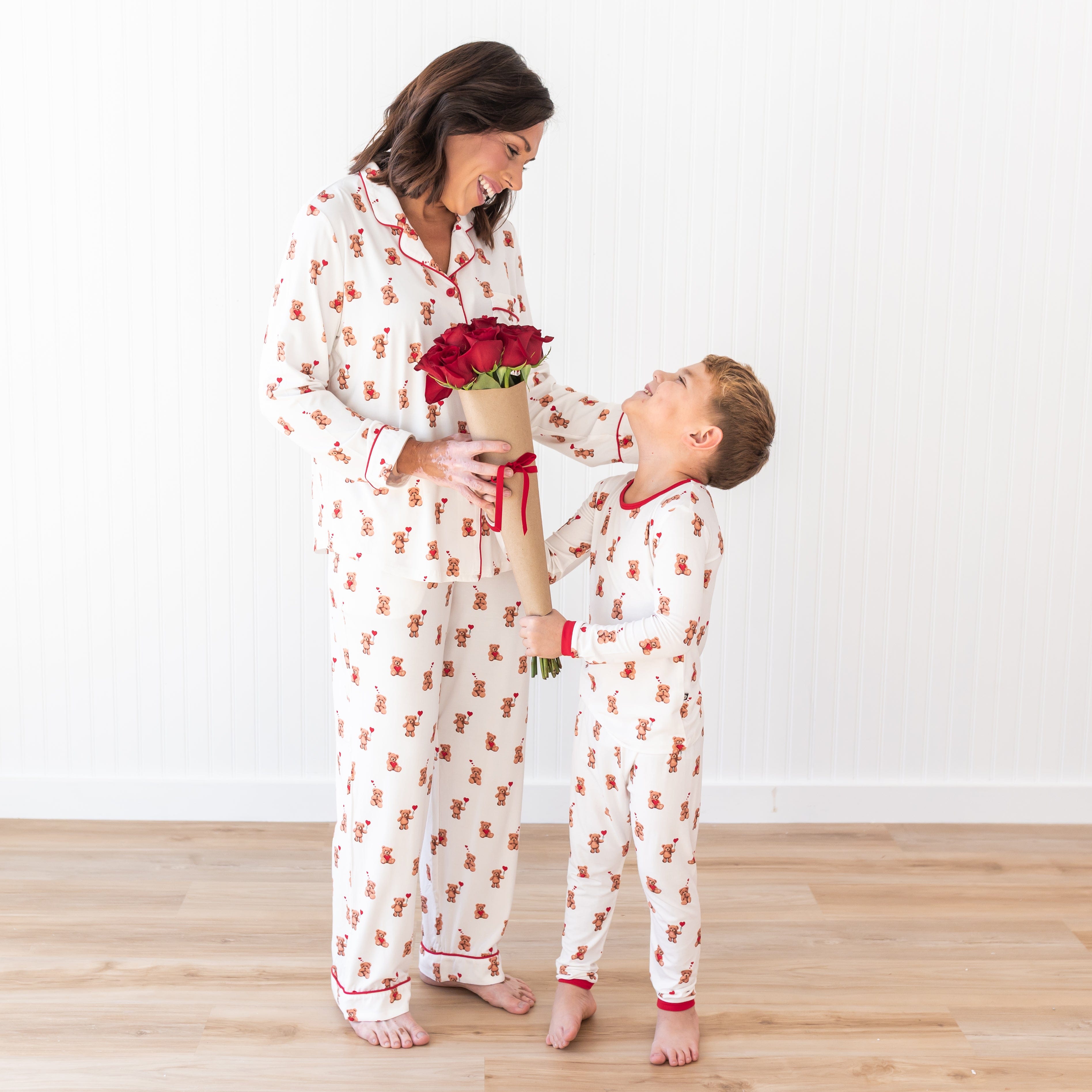 Mother and son smiling looking at one another holding flowers wearing matching Bear Hearts pajama sets