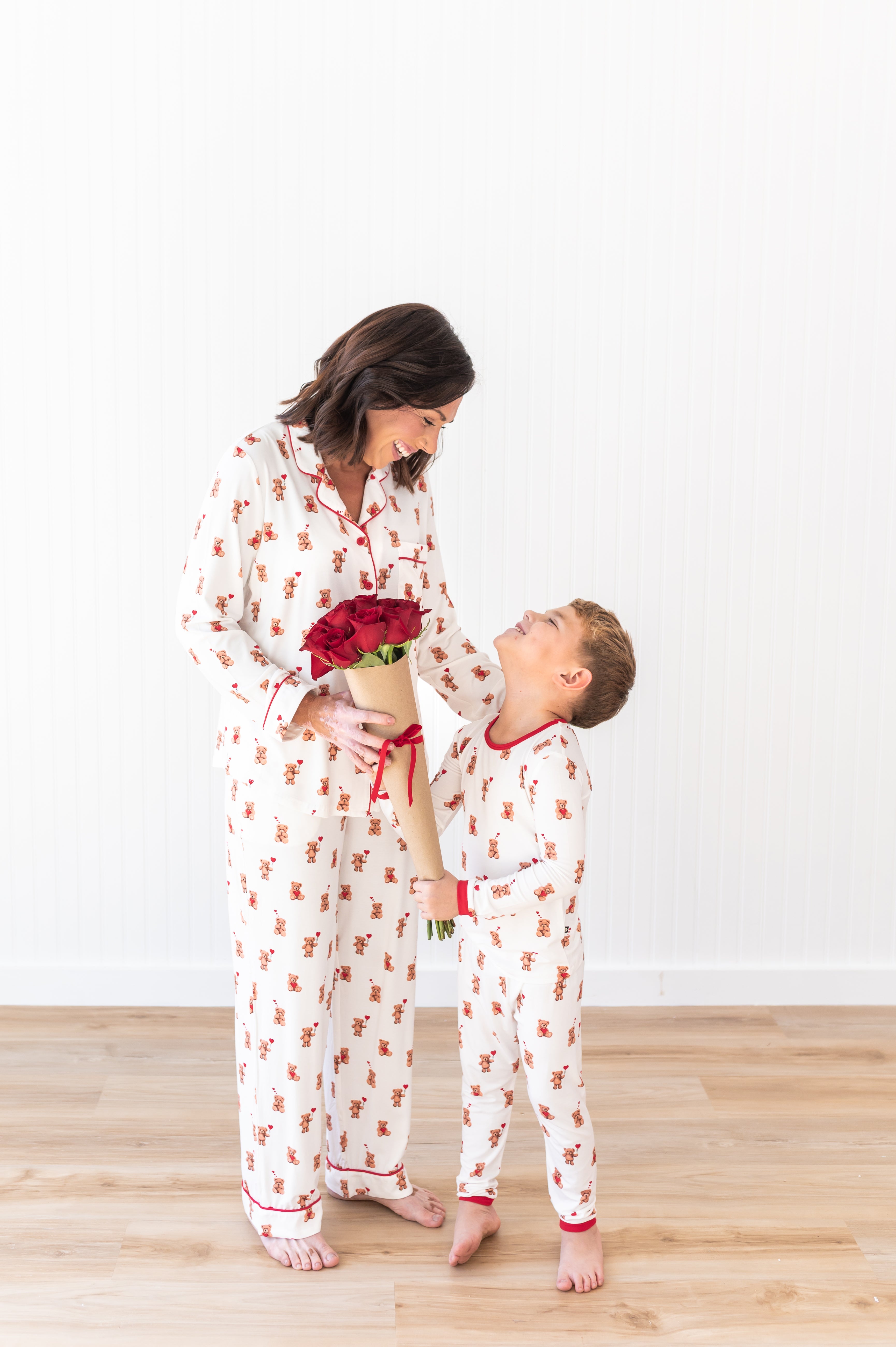 Mother and son looking at one another holding flowers wearing matching pajamas in the print Bear Hearts