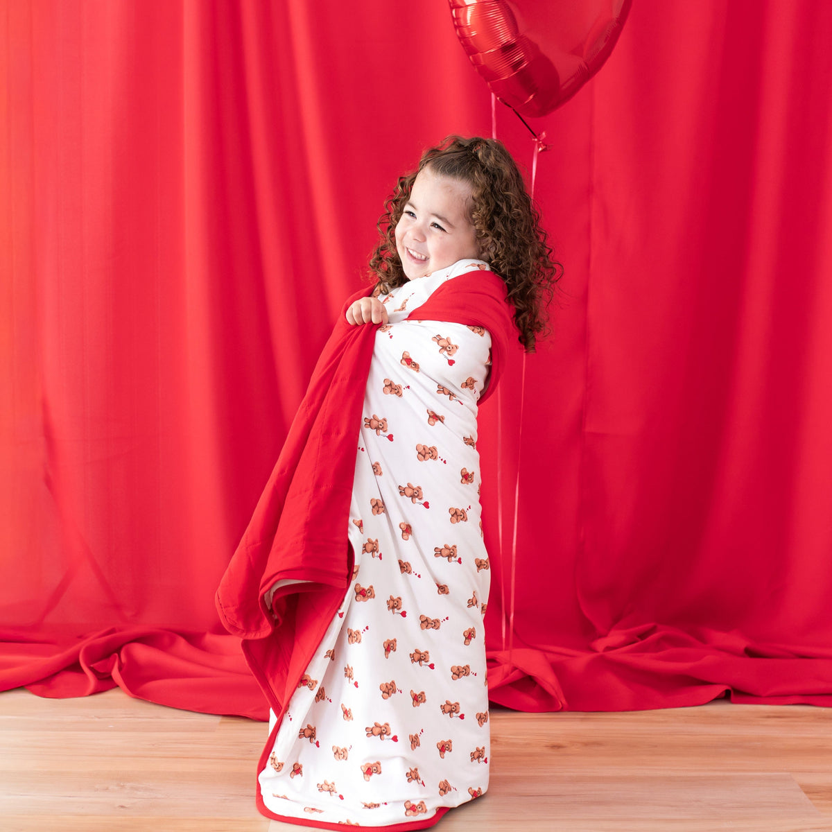 Young girl smiling standing with the soft Toddler Blanket in Bear Hearts 1.0 wrapped around her