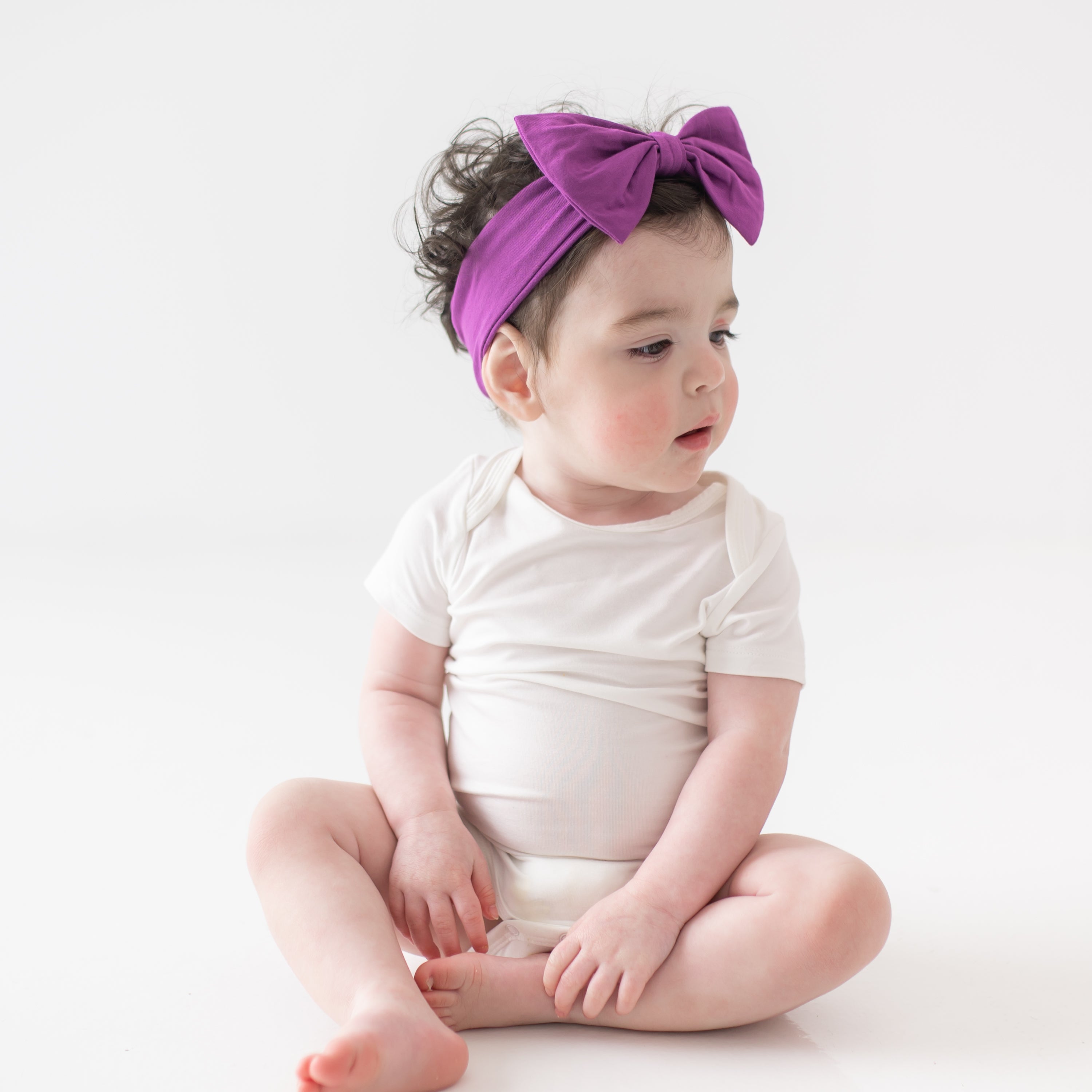 Baby sitting wearing cloud bodysuit and Bow Headband in Berry