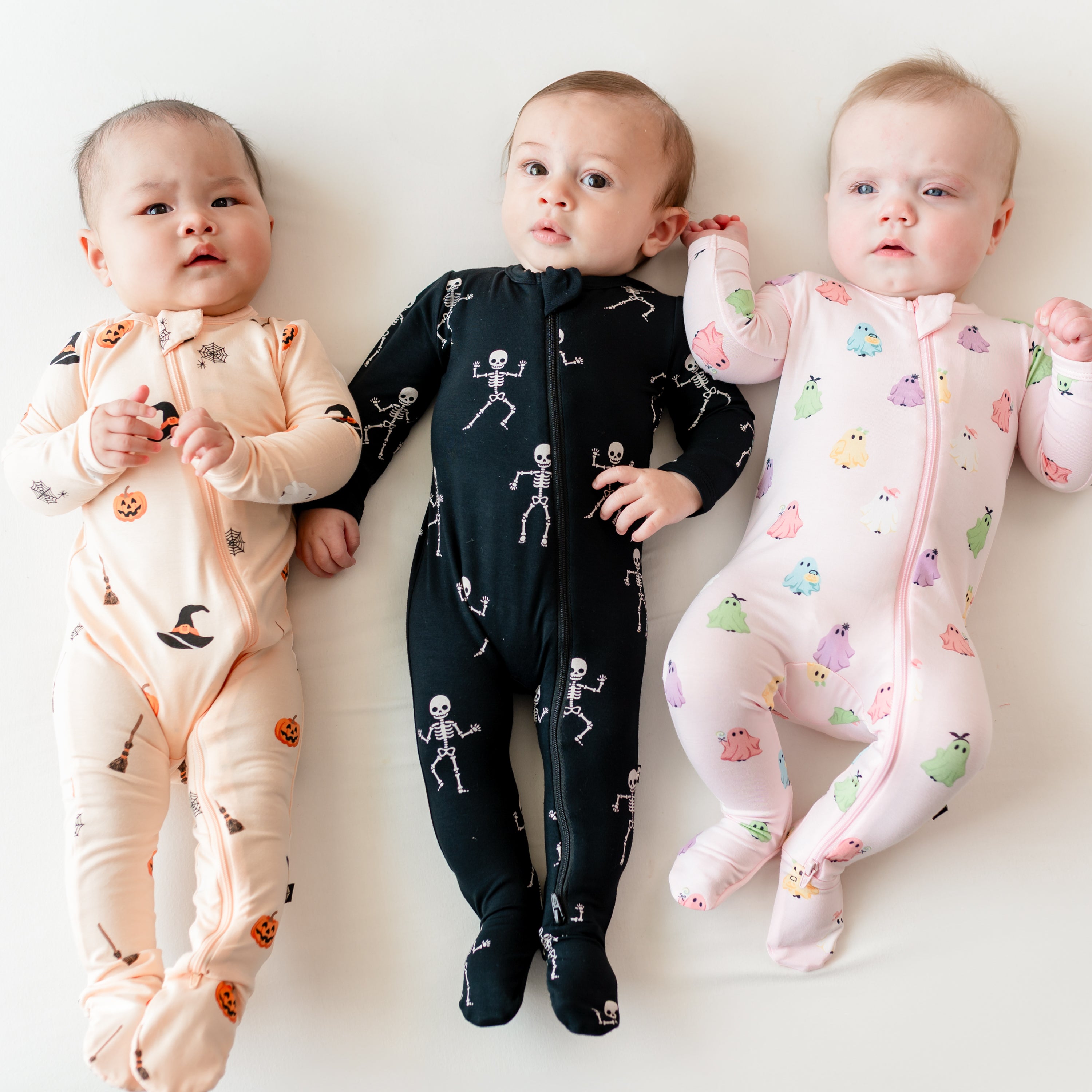 Three infants wearing the Zippered Footie Halloween kids pajamas in Skeleton, Bewitched and Pastel ghosts