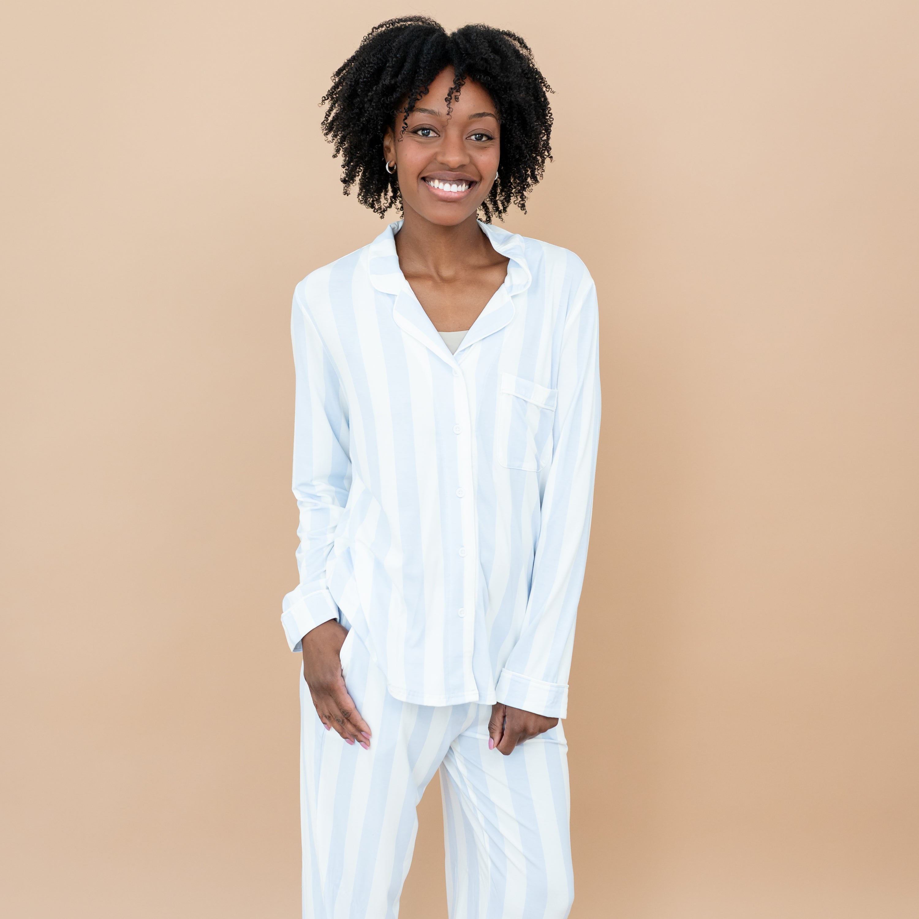 Close up of smiling female model wearing the Long-Sleeved Women's Pajama Set in Big Mist Stripe with one hand in pants pocket