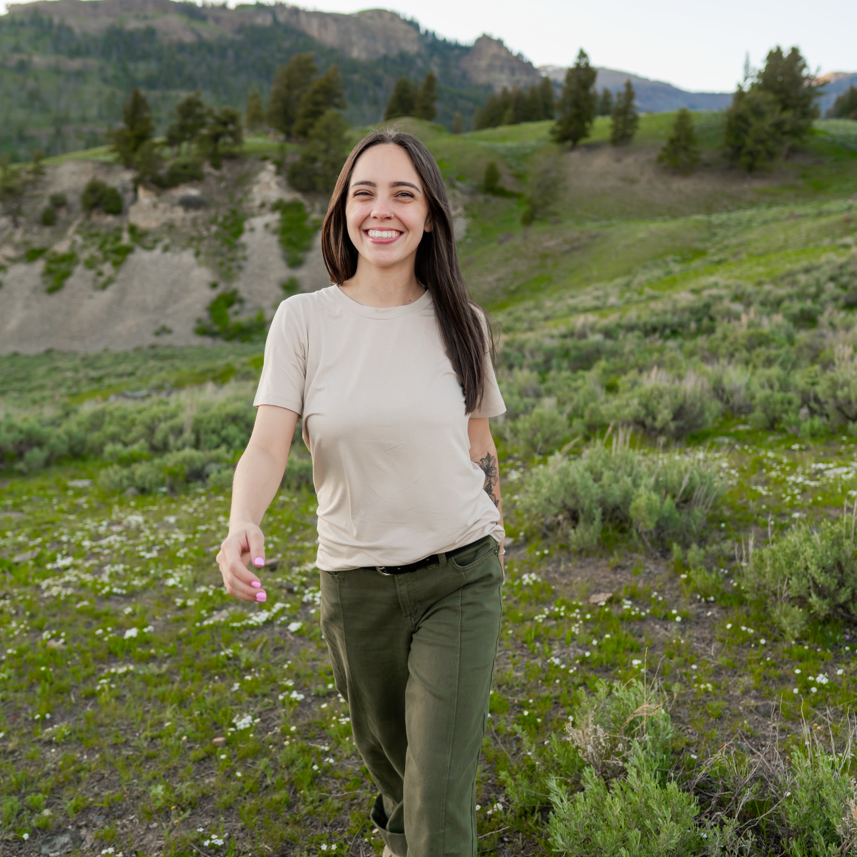 Smiling model walking through a field wearing the Women's Crew Neck Tee in Bisque