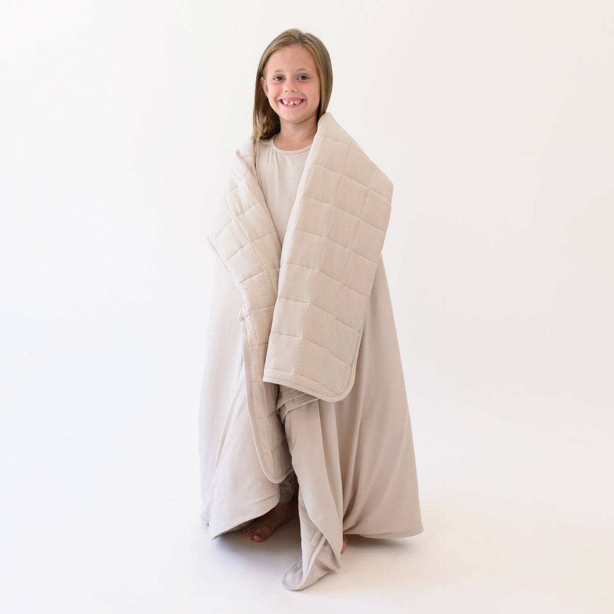 Smiling young girl model standing wrapped in the Youth Blanket in Bisque 2.5