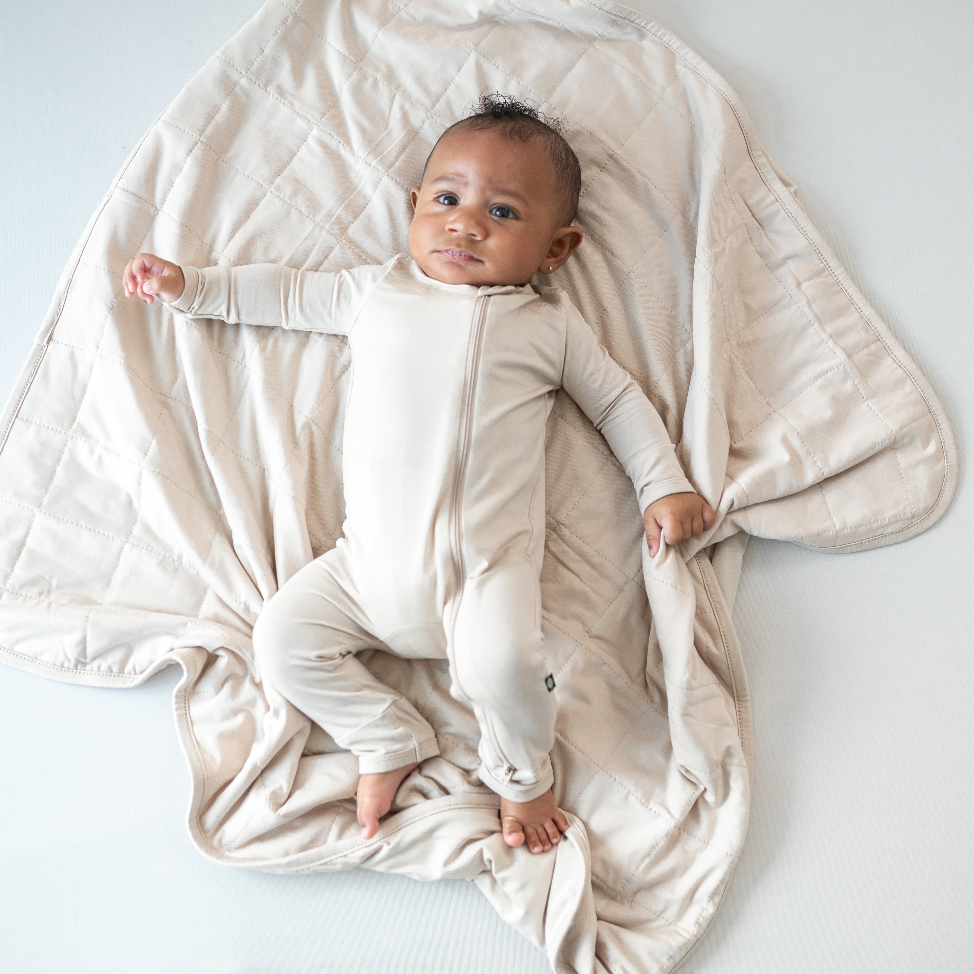 Infant wearing Bisque neutral romper pajamas laying on Baby Blanket in Bisque TOG 1.0