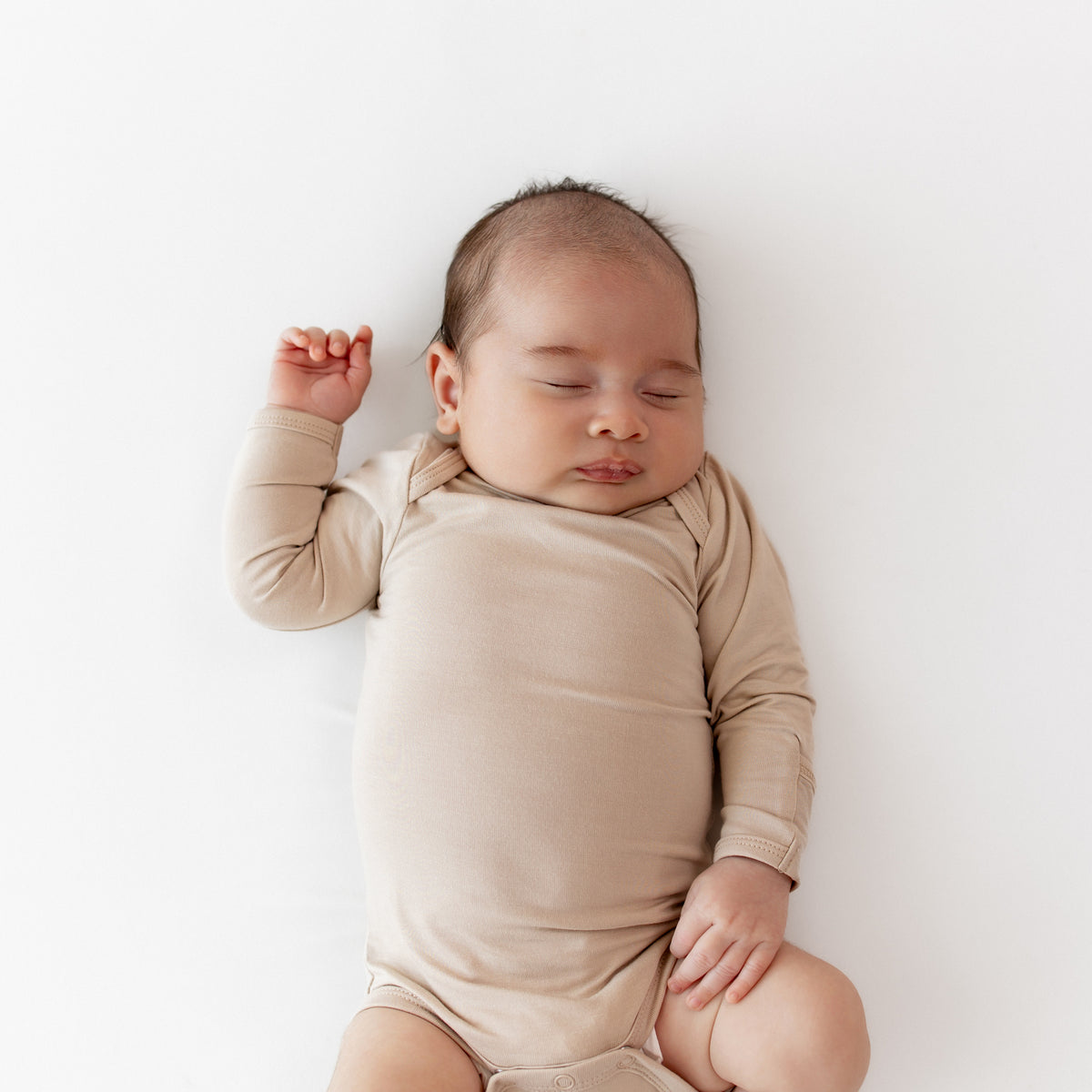 Close up of sleeping newborn wearing the Long Sleeve Bodysuit in Bisque