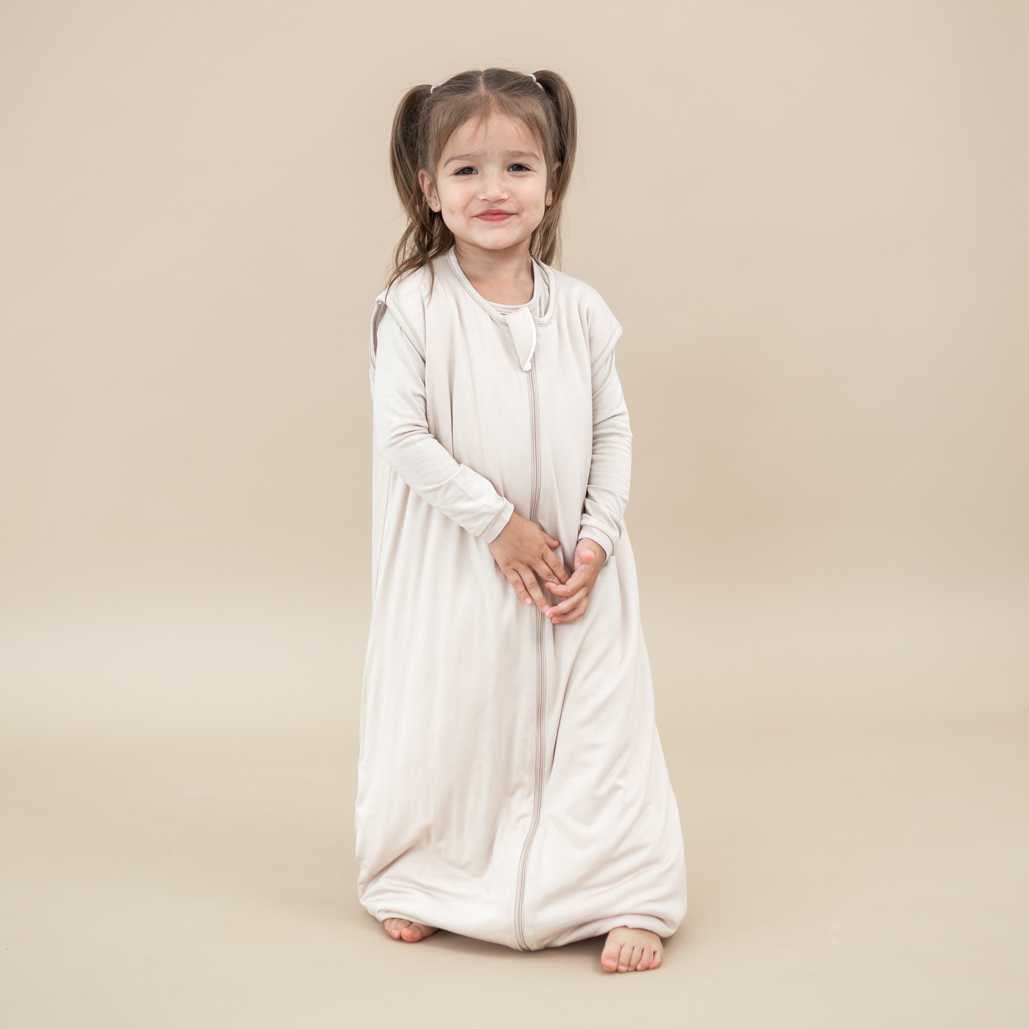 Young girl model wearing the Sleep Bag Walker in Bisque 1.0 with matching long sleeve toddler pajamas on underneath