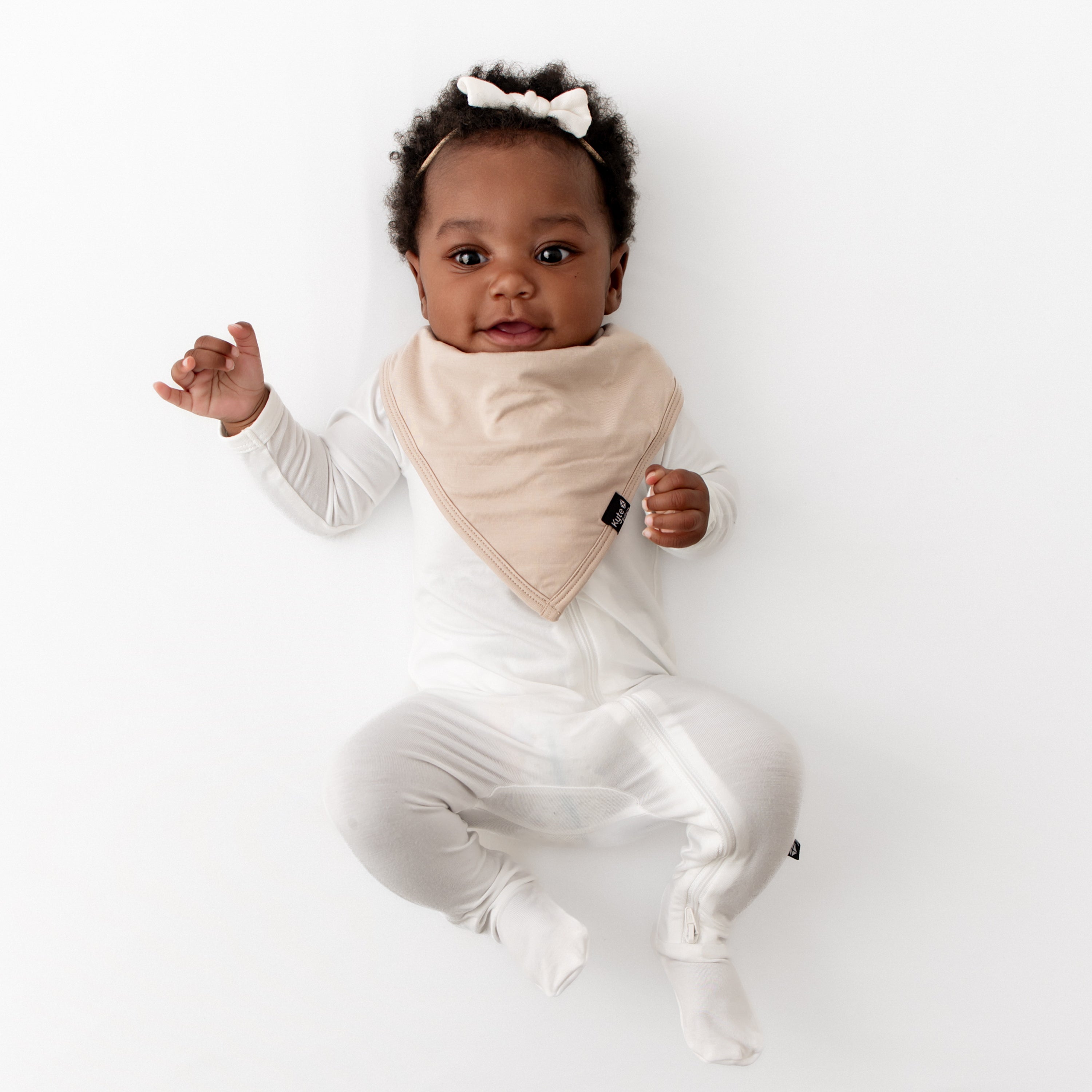 Infant wearing the Bib in Bisque overtop a Cloud Zippered Footie