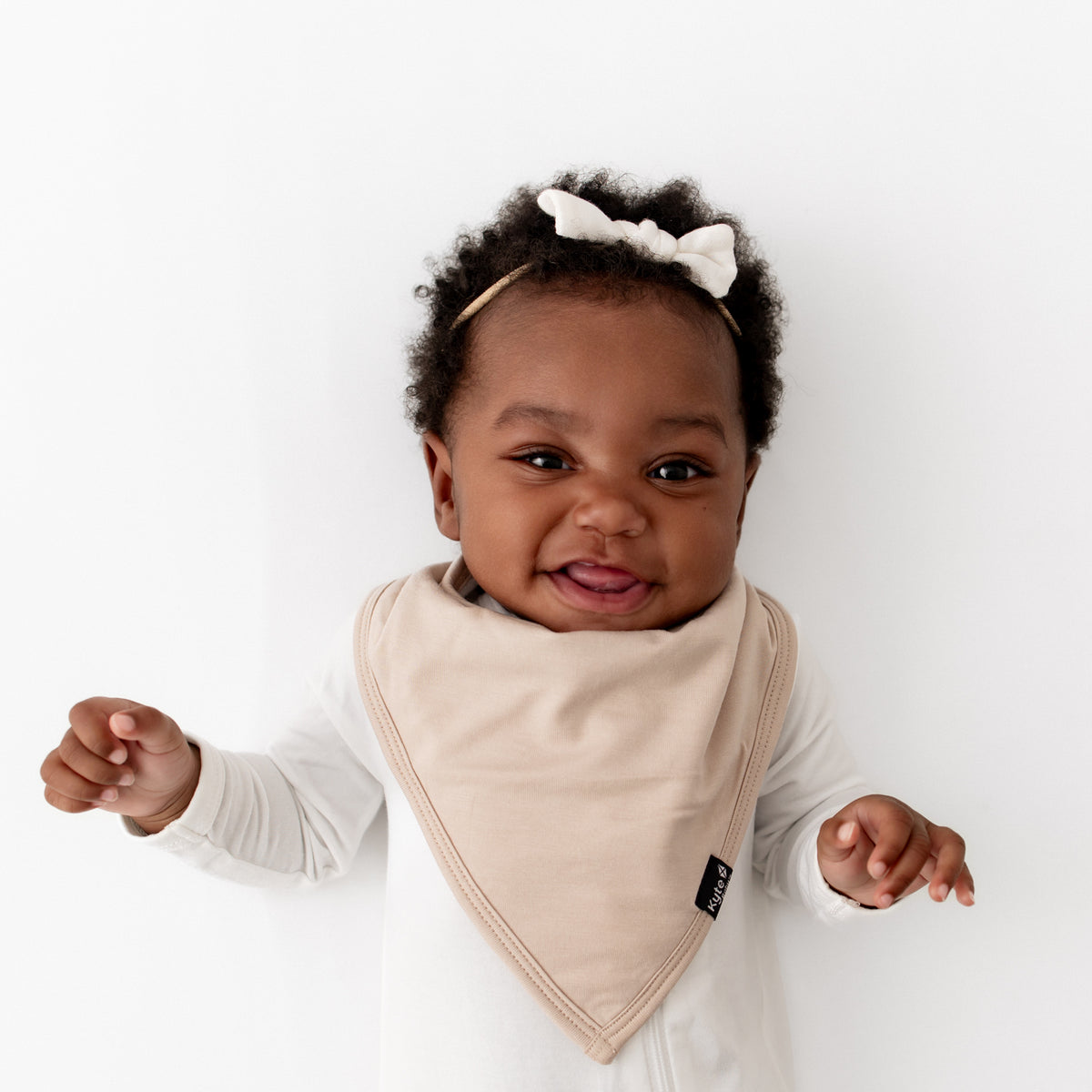 Infant wearing the Bib in Bisque overtop a Cloud Zippered romper