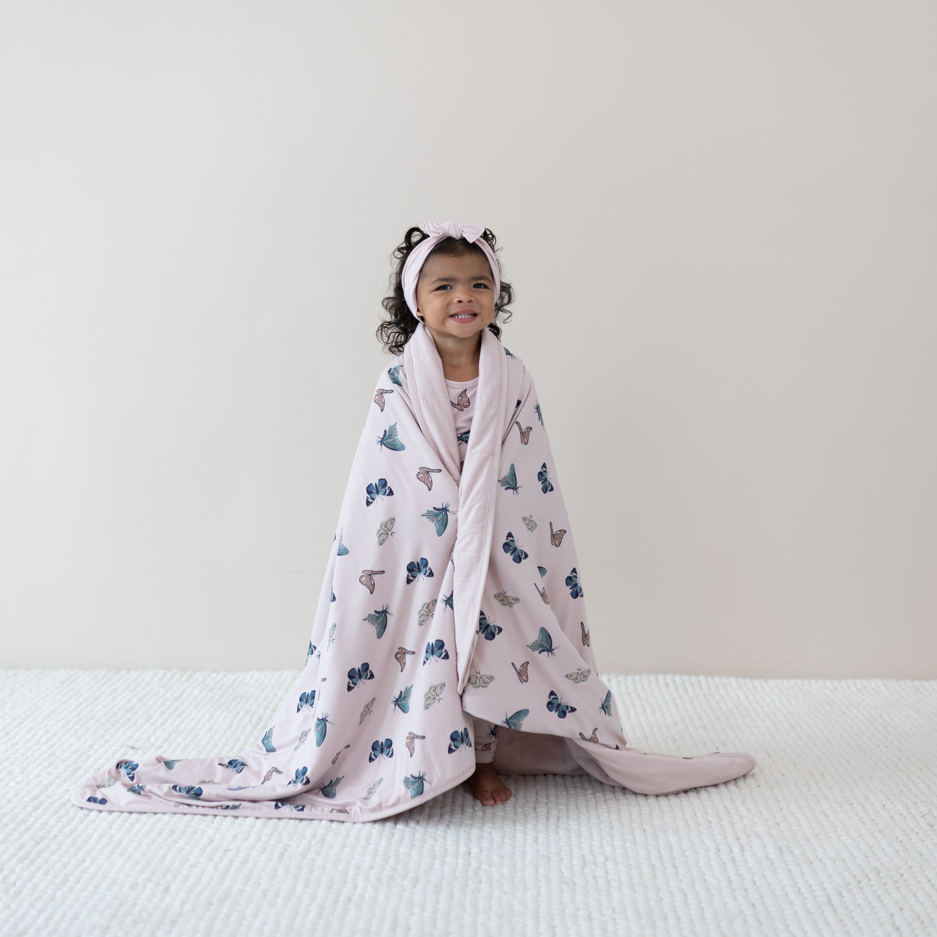 Child wrapped in Youth Blanket in Blush Butterfly 2.5