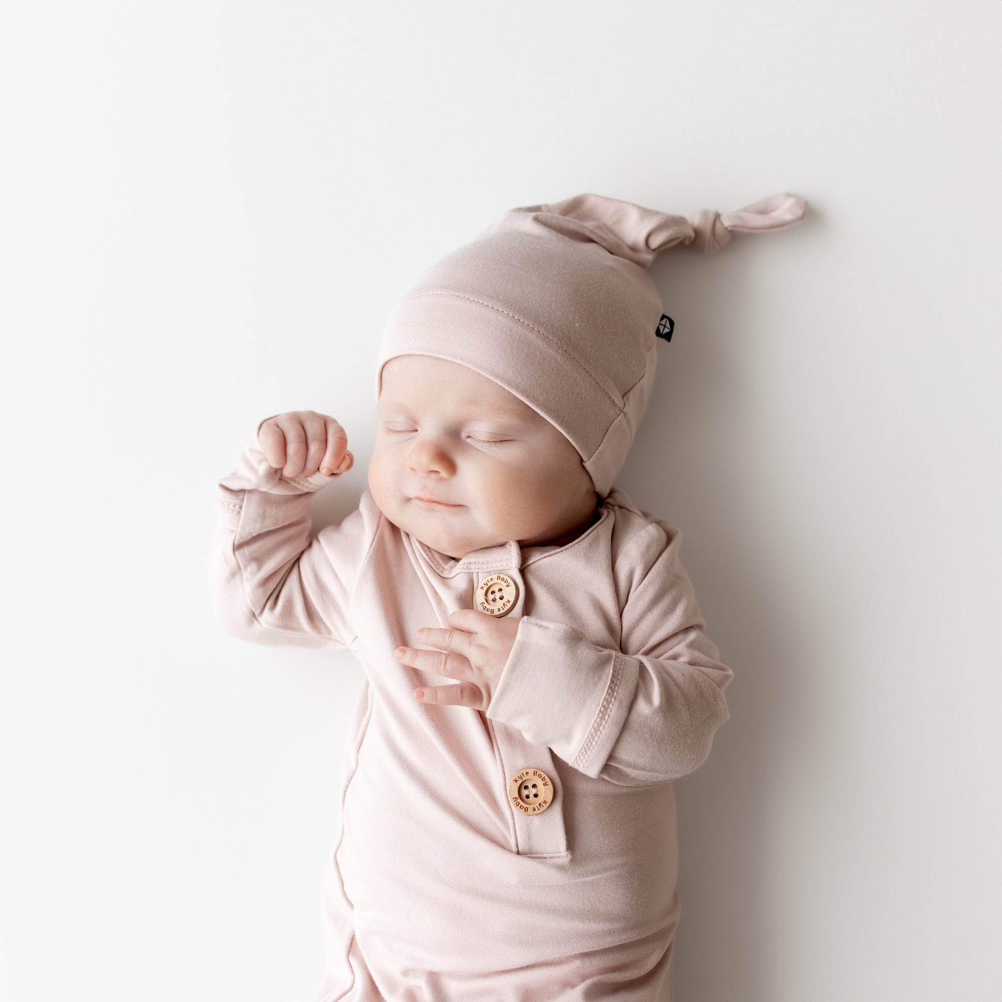 Baby in pink outfit and hat sleeping on a white background