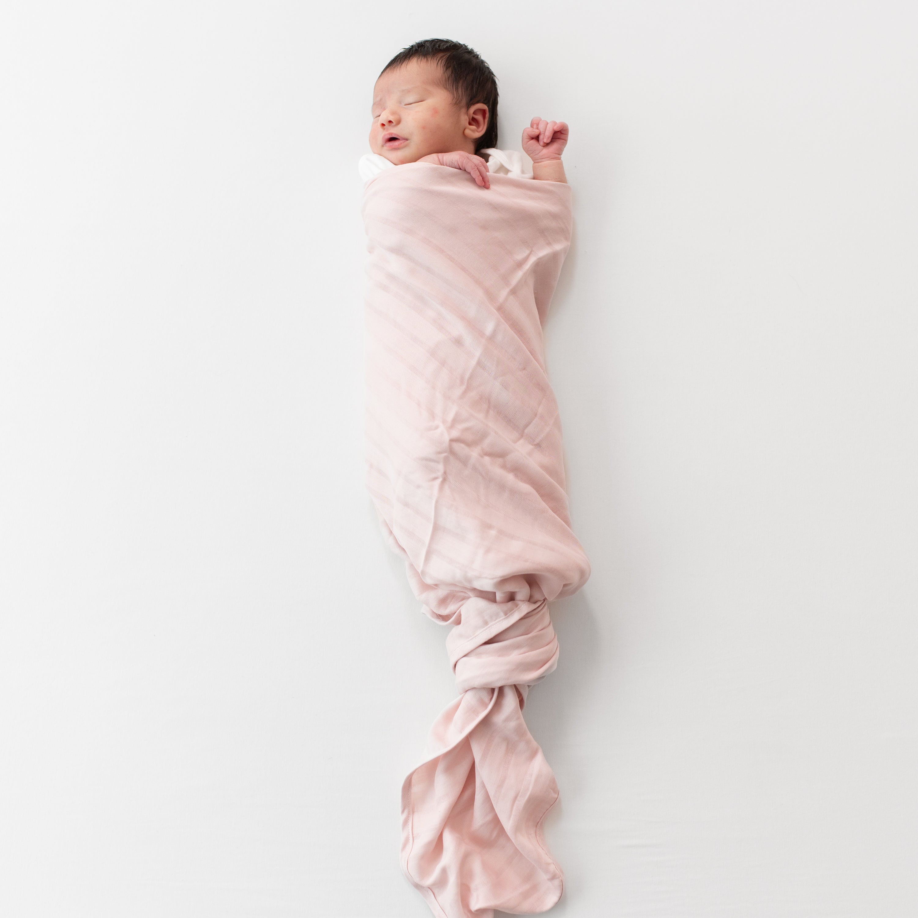 Baby swaddled in Bamboo Muslin Swaddle Blanket in Blush Pink