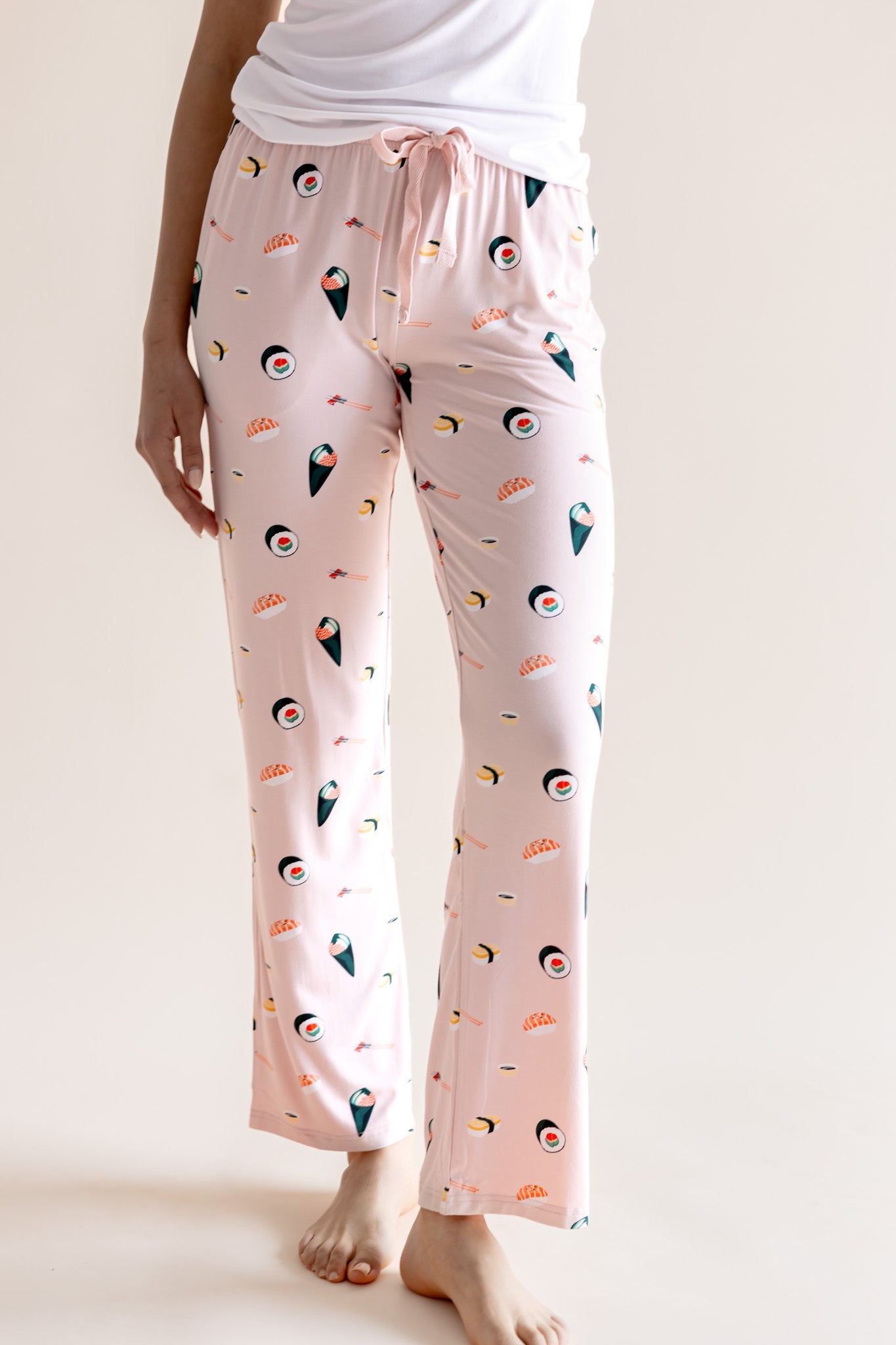 Model wearing pink Women's Lounge Pants with drawstring in Sushi print under white camisole on a beige background